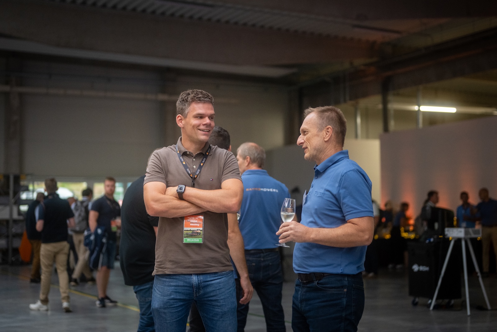 Two attendees talking with a glass of wine in the production hall