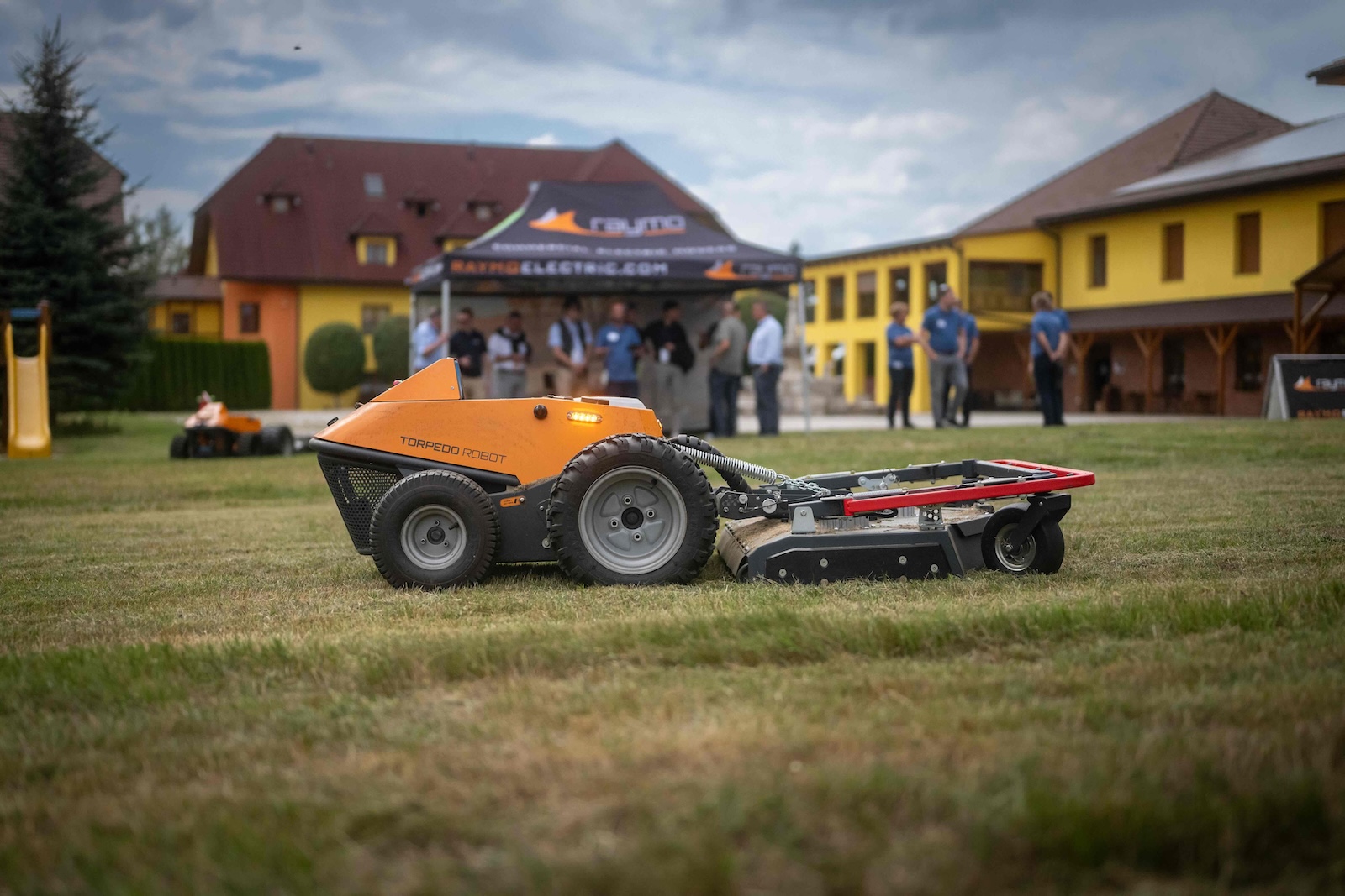Torpedo Robot with rotary deck mowing the lawn in front of the hotel buildings