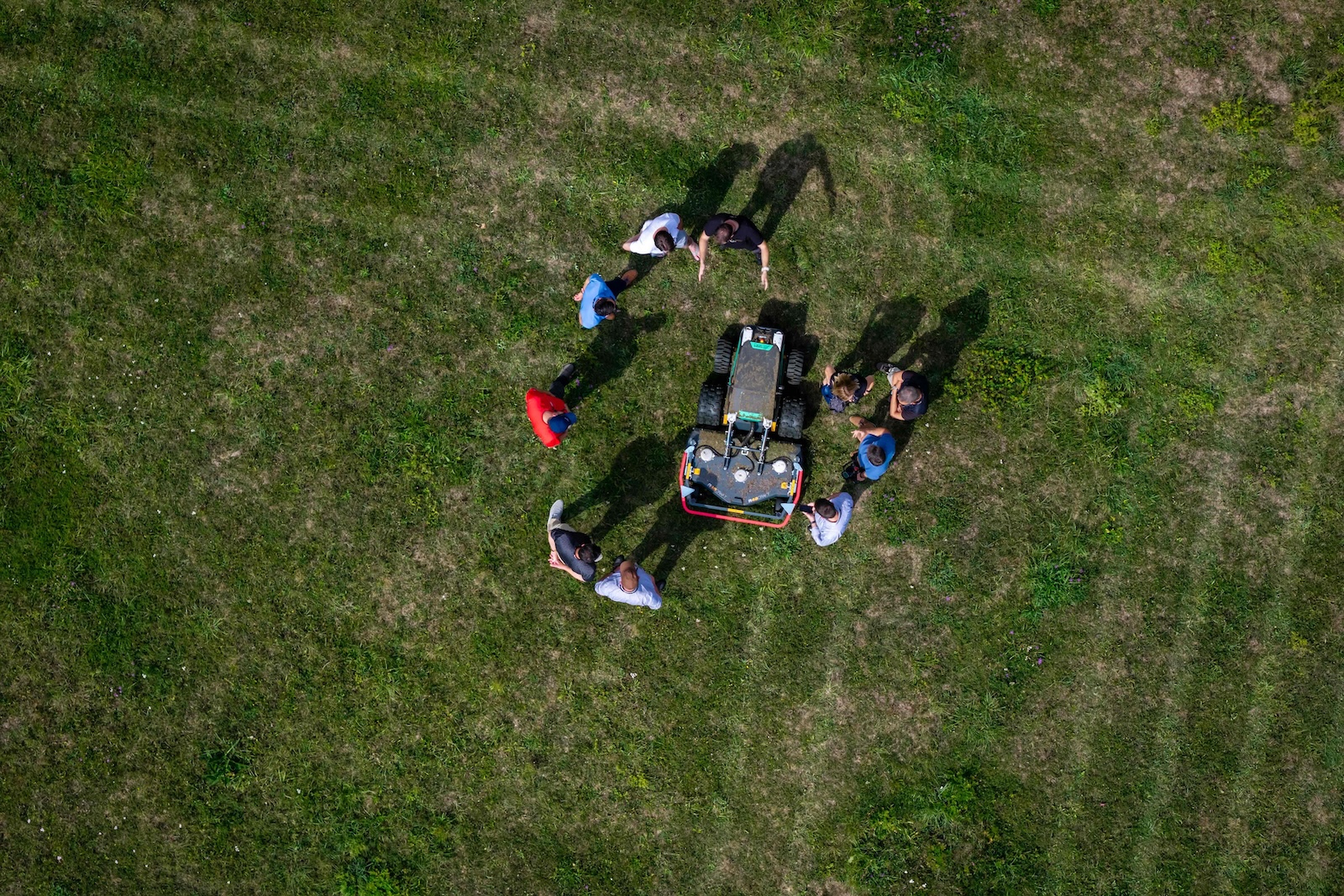 Top-down aerial view of a group around a Raymo robot in the meadow