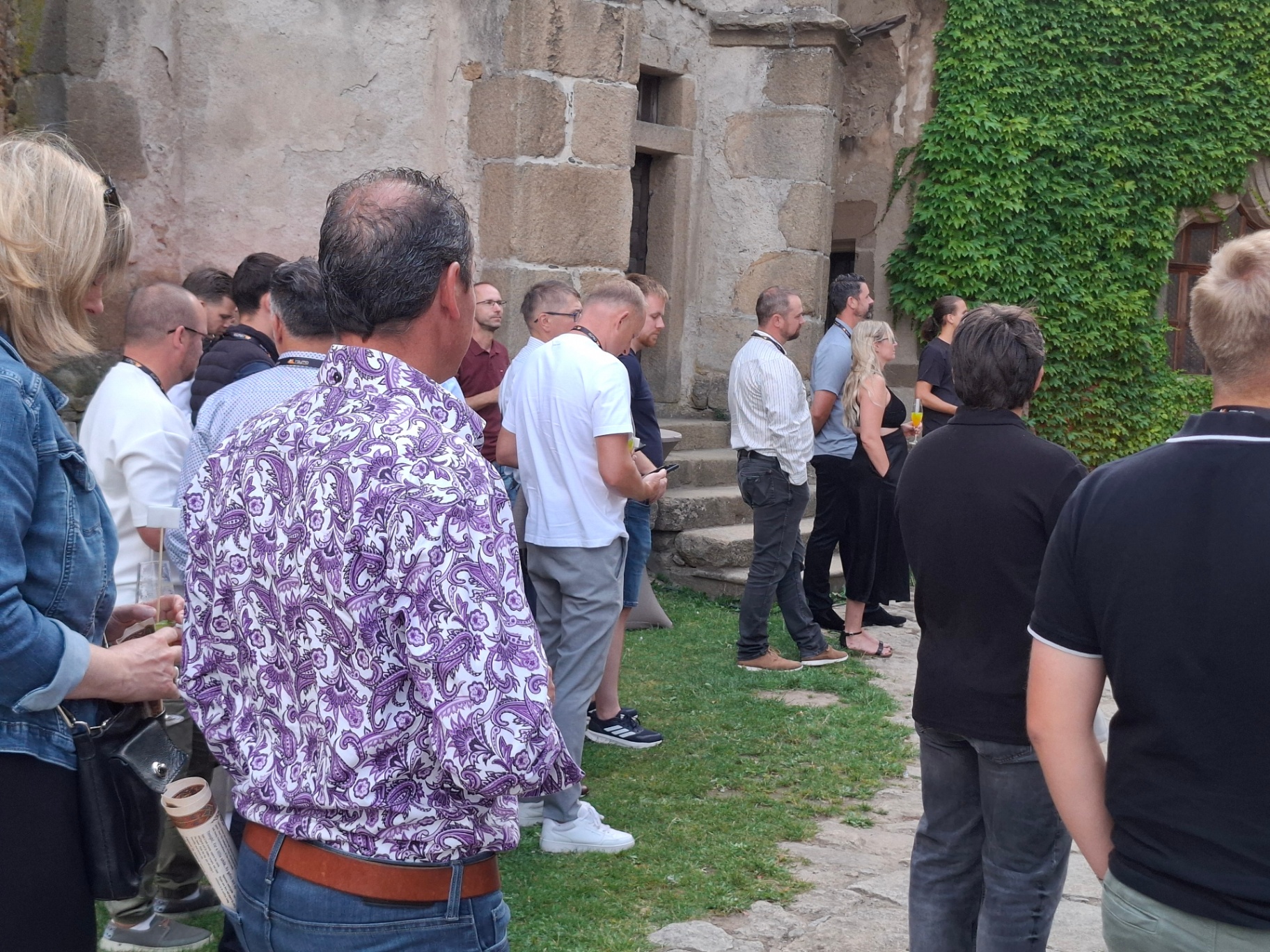 Attendees chatting in front of the ivy-covered castle wall
