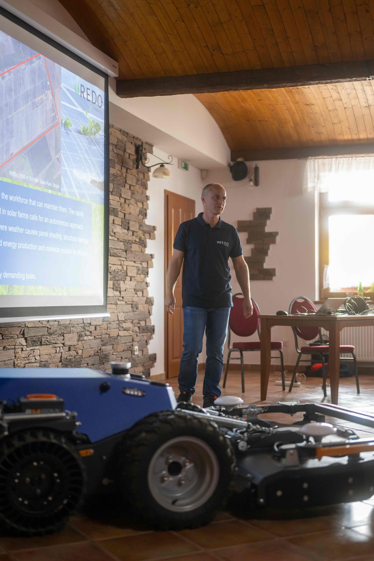REDO Robotics speaker presenting solar farm maintenance next to the blue robot