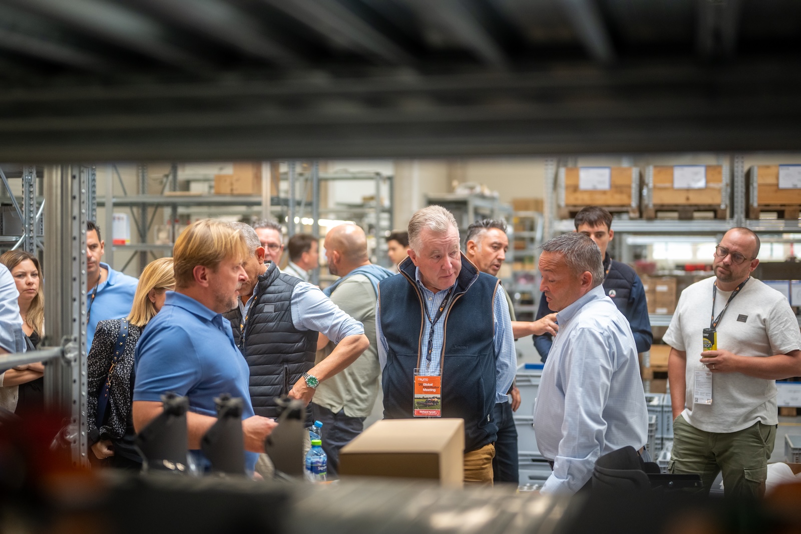 Distributors talking among the warehouse racks during the factory tour