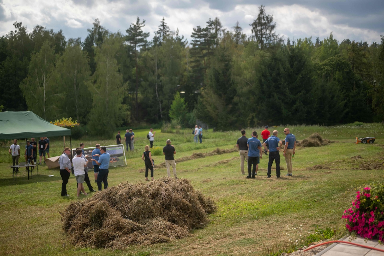 Wide view of the demo field with attendees, tents and rows of cut grass