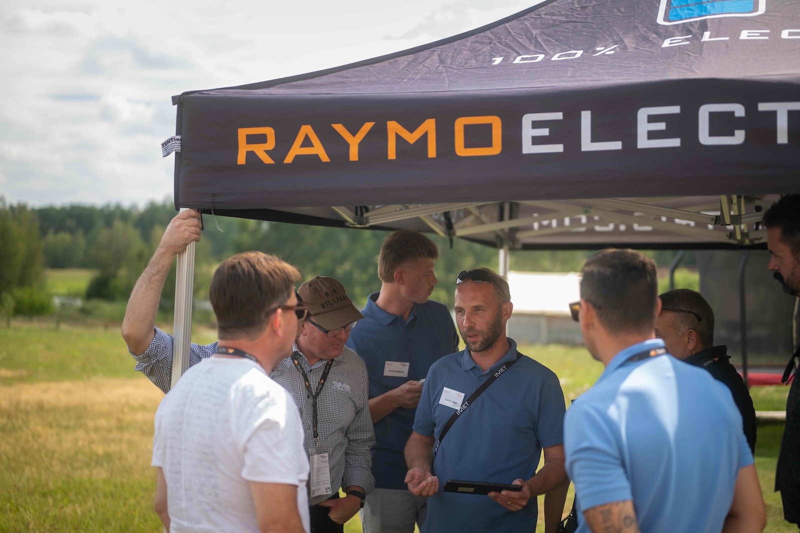 Group talking under the Raymo Electric tent during the demo rotation