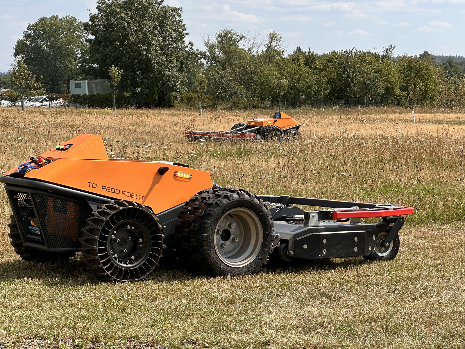 Two Torpedo robots mowing tall grass in the field