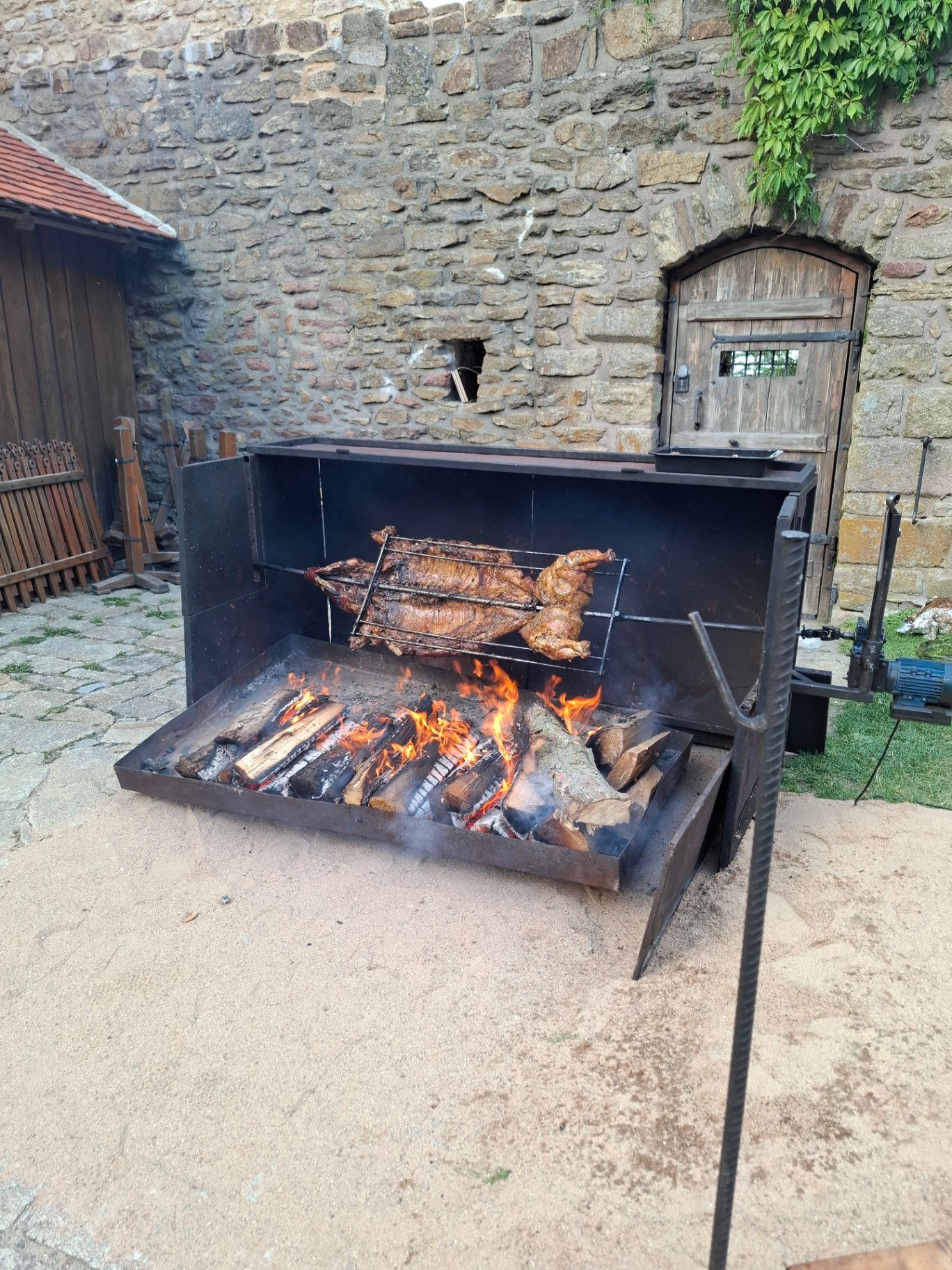 Whole pig roasting on an open fire grill in the castle yard