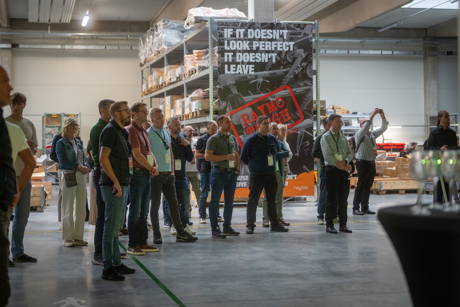 Distributors listening in the production hall by the Raymo Tough banner