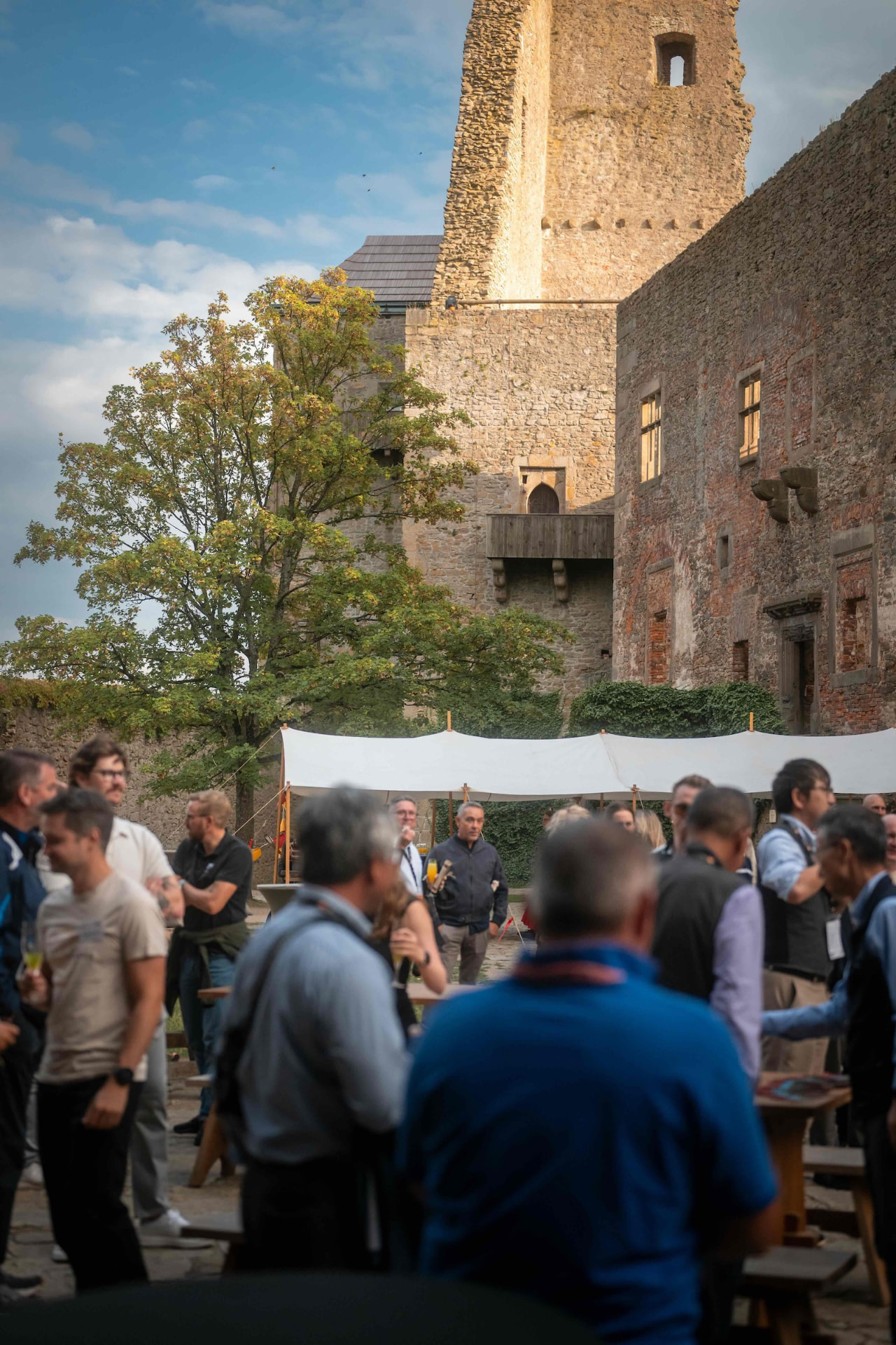 Guests with drinks in the courtyard with the castle tower in the evening light