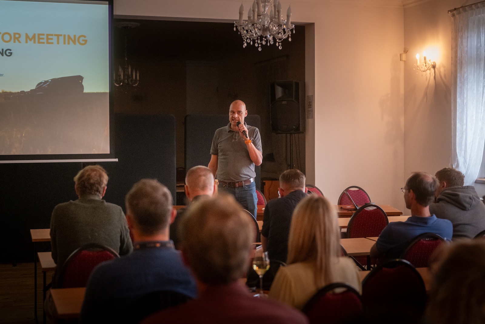 Speaker with a microphone in front of the Global Distributor Meeting presentation