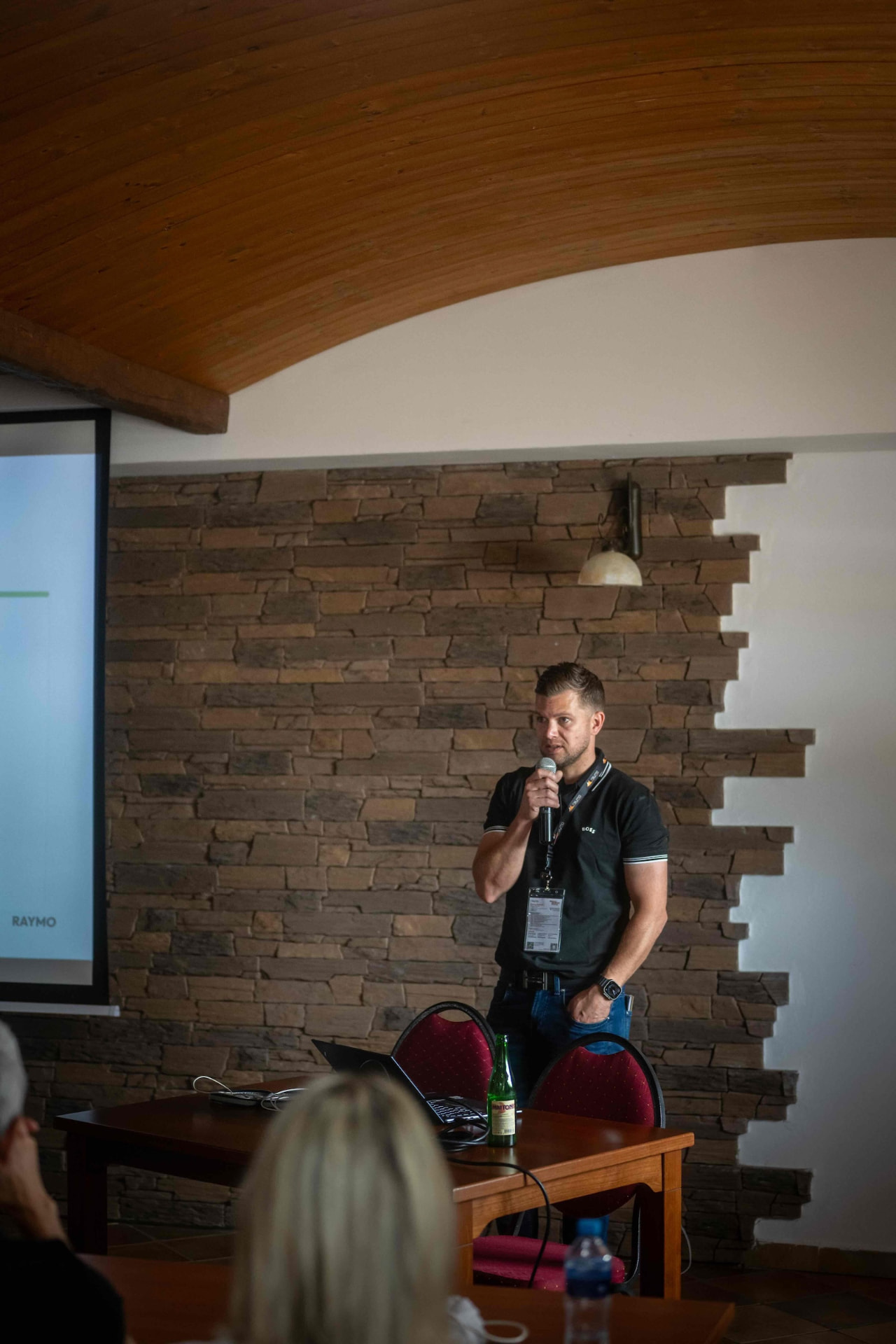 Speaker with a microphone in front of the stone wall of the conference room