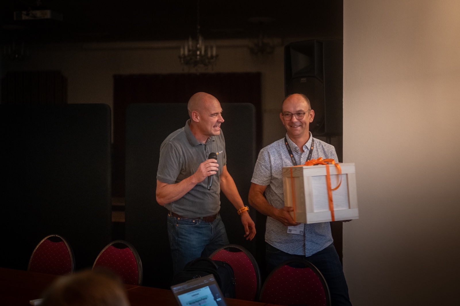 Hosts handing over a wooden gift box on stage