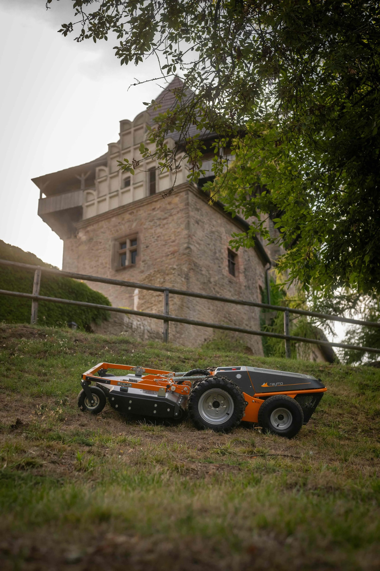 Orange Raymo carrier with mowing deck on the slope below Lipnice Castle