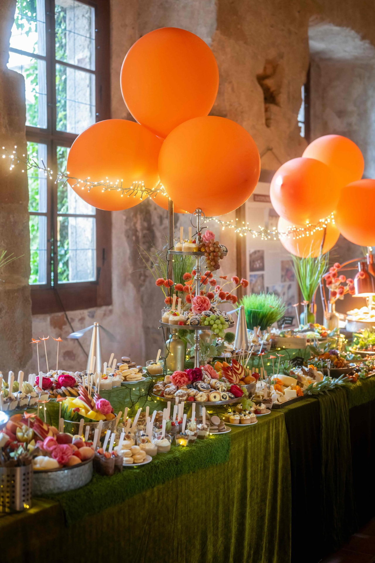 Dessert table with orange balloons and flower decorations at the gala dinner