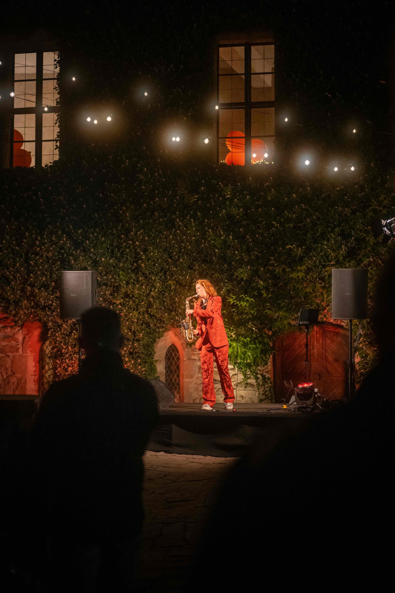 Saxophonist in a red suit performing on the castle courtyard stage