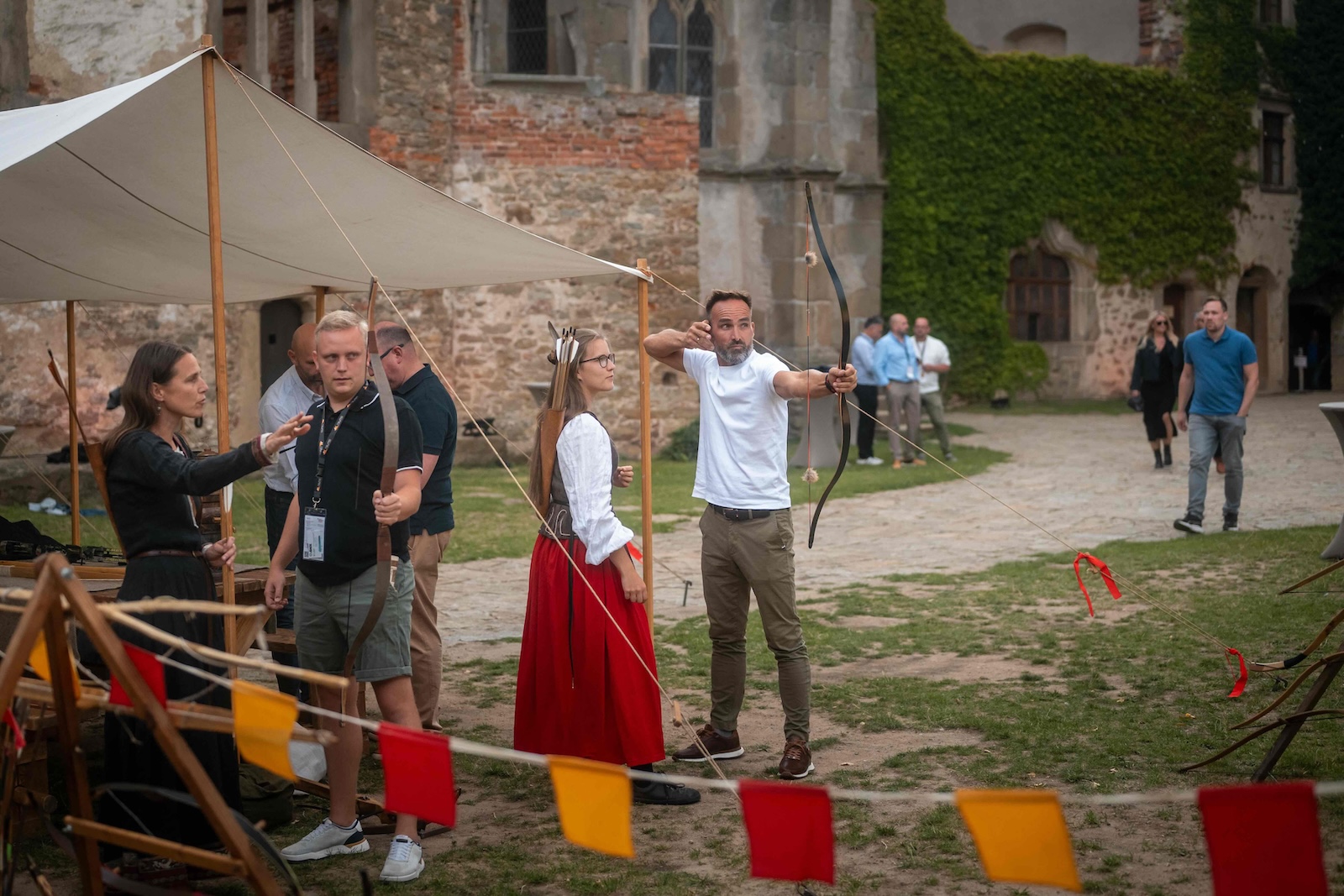 Guest shooting a bow while others wait their turn at the castle