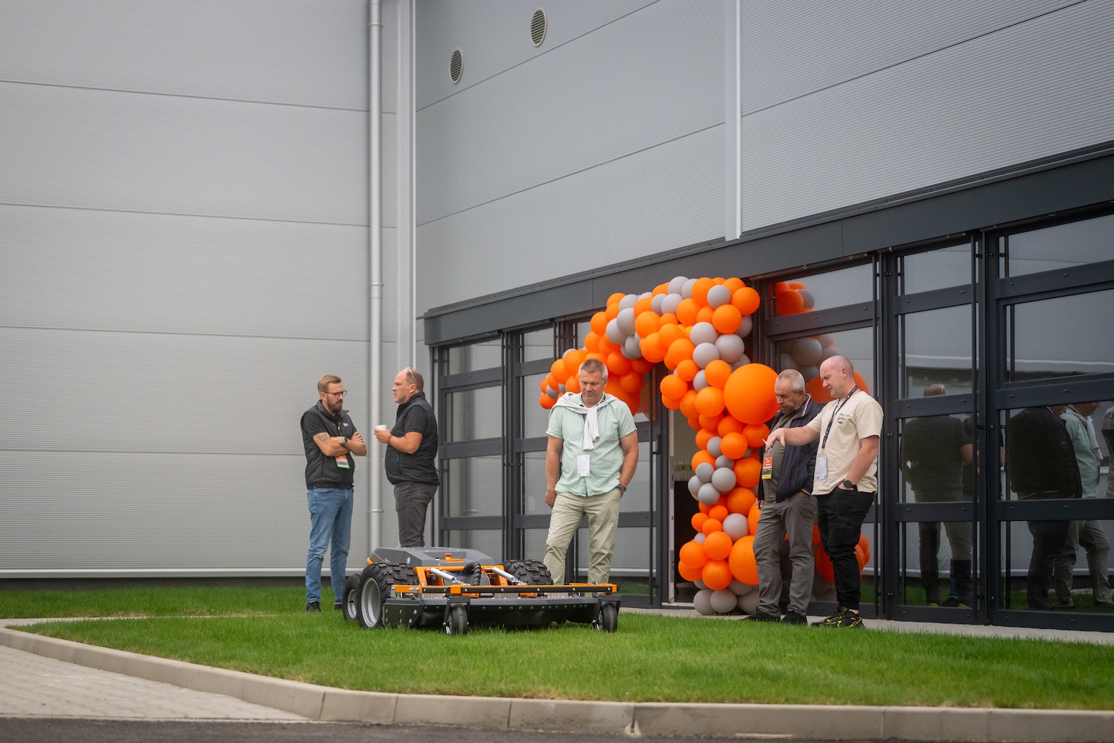 Guests with a Raymo mower outside the new hall by the balloon arch