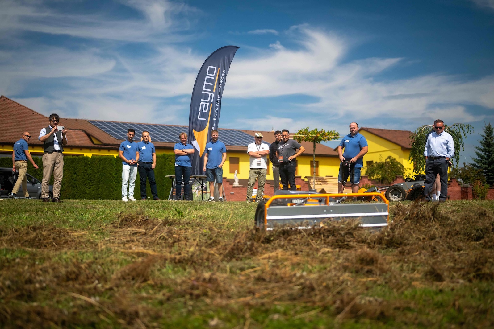 Group watching a Raymo machine with a flail deck working the field