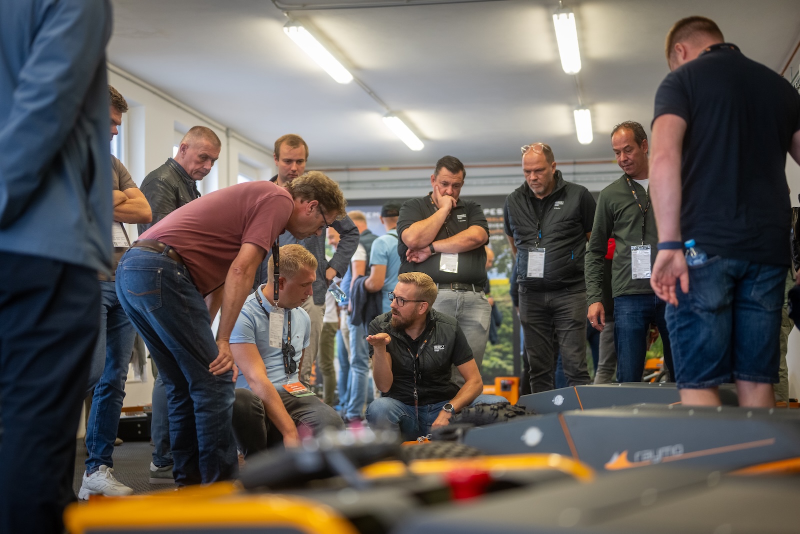 Group crouching around a Raymo mower during a technical explanation