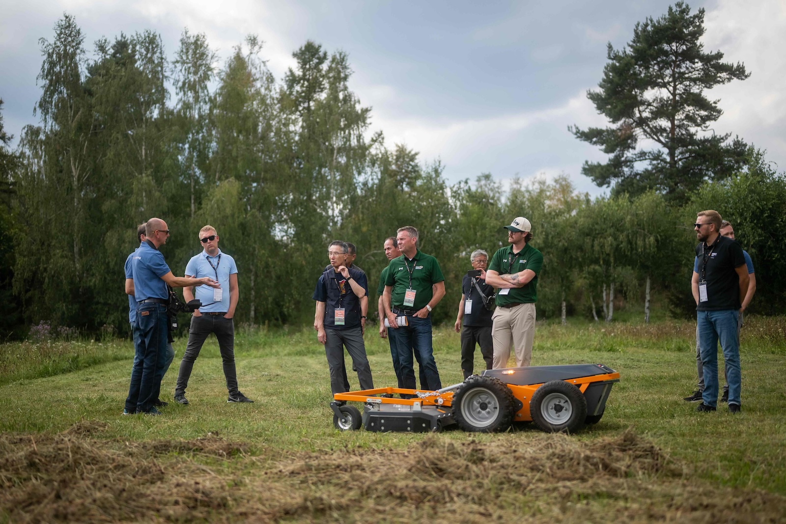 Distributors listening to a specialist next to an orange carrier with mowing deck