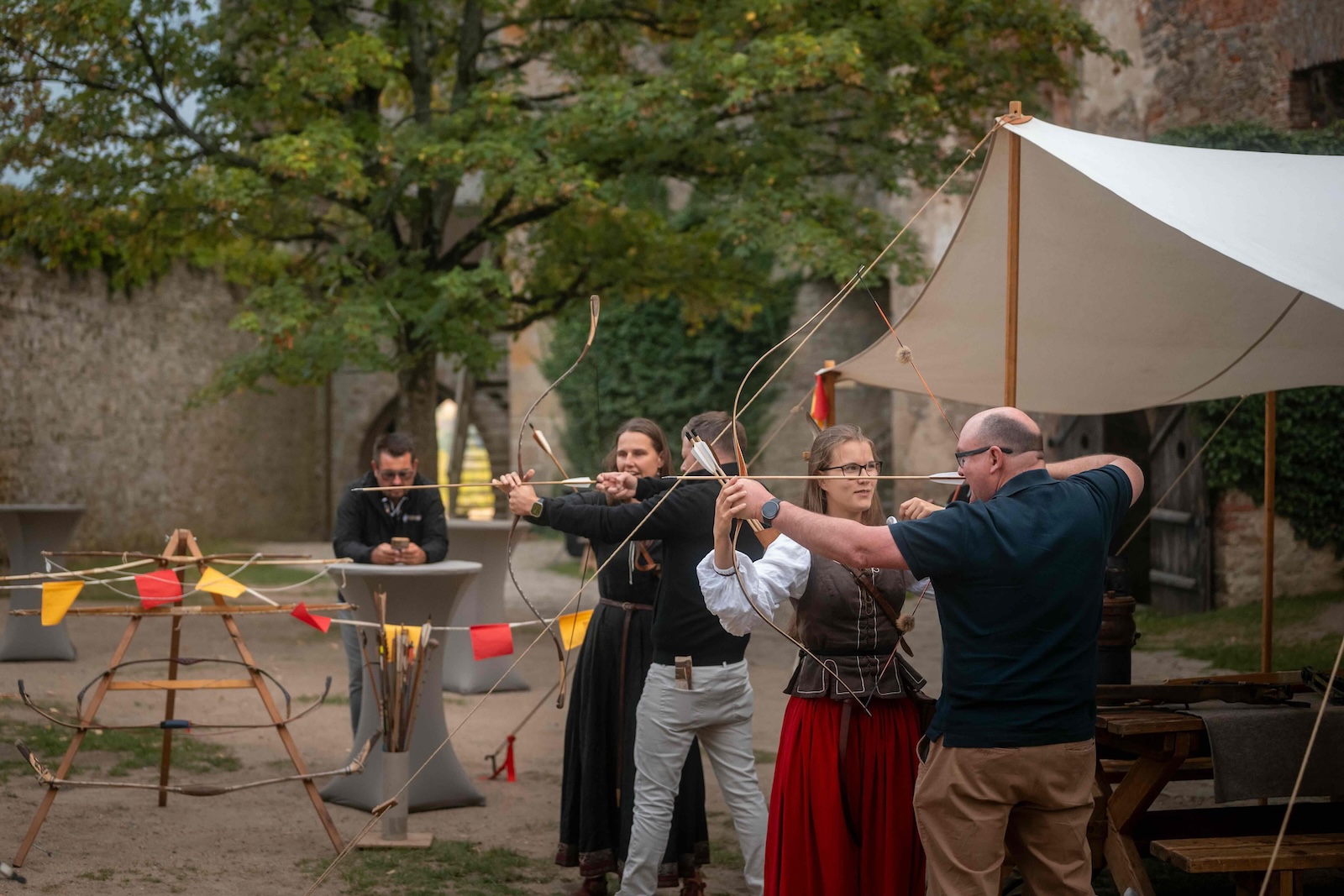 Several guests drawing longbows side by side during the archery session