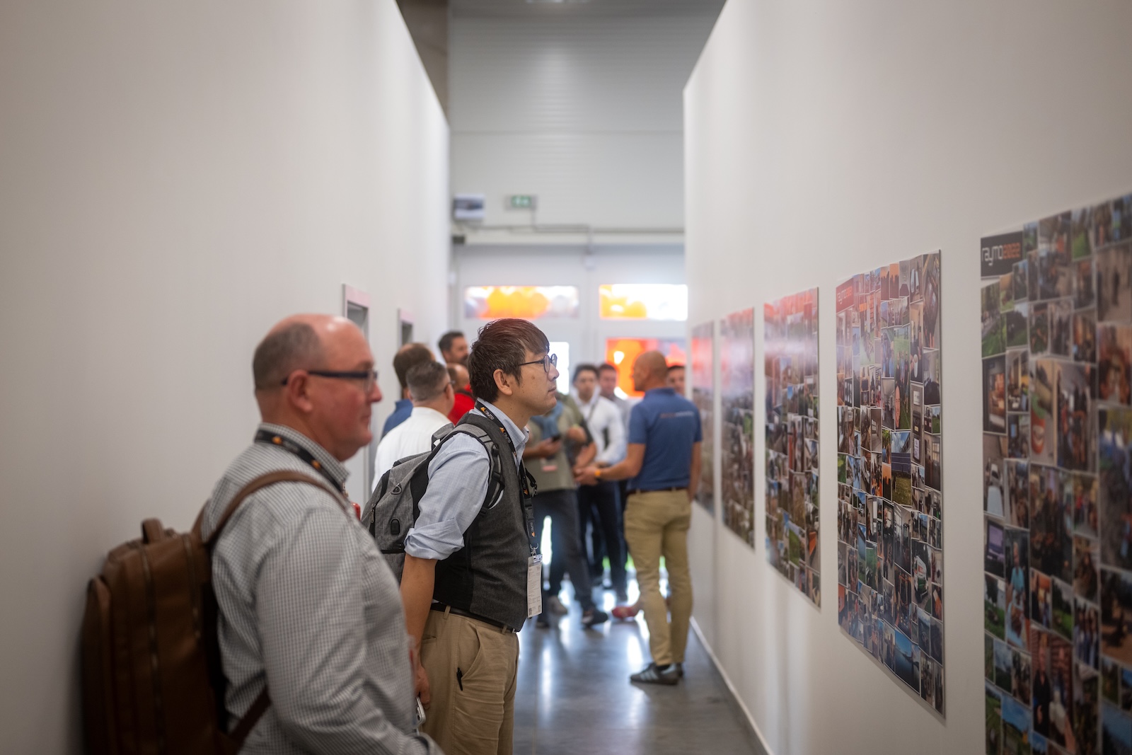 Guests viewing the Raymo photo collage exhibition in the hall corridor