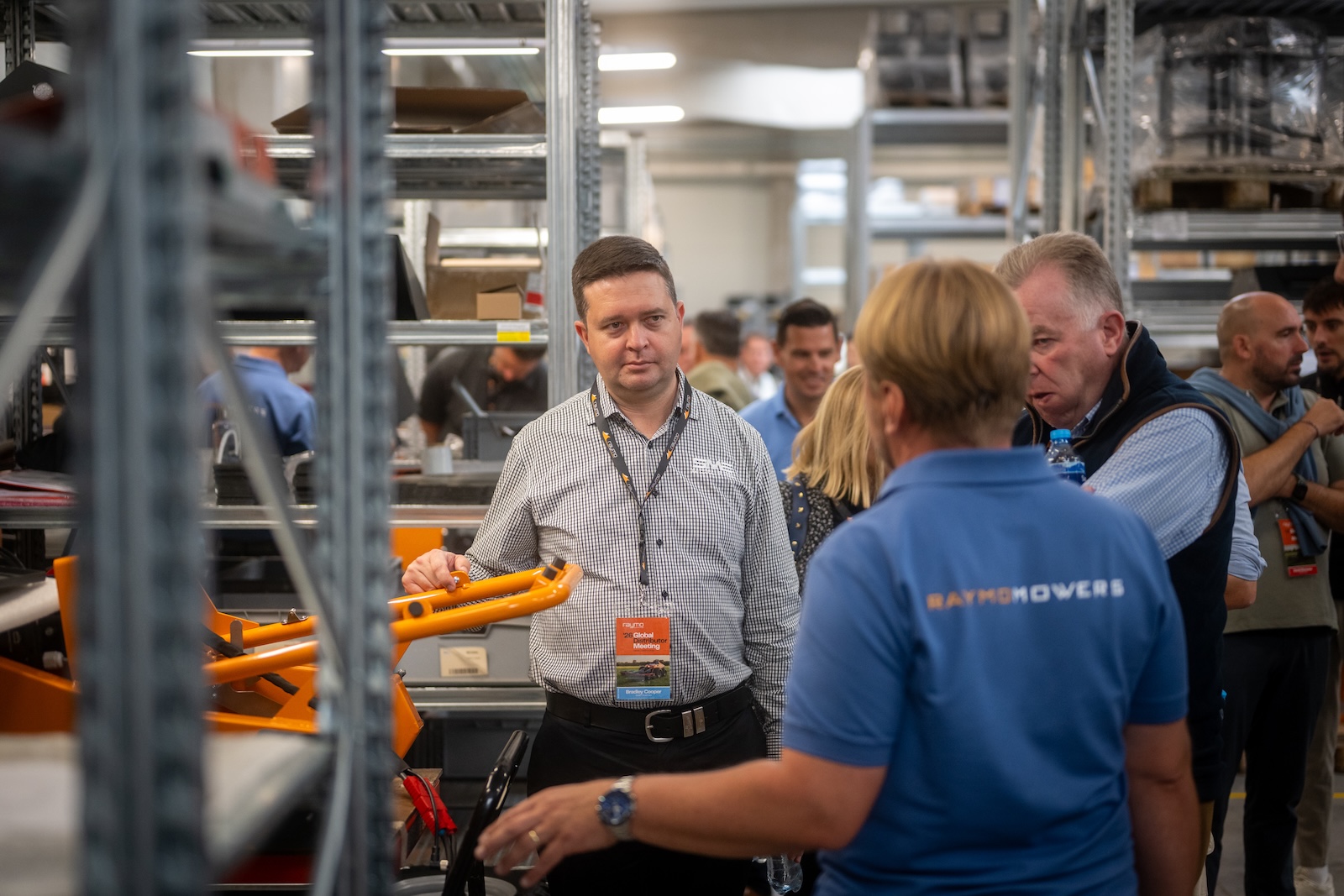 Guests inspecting an orange attachment frame in the workshop