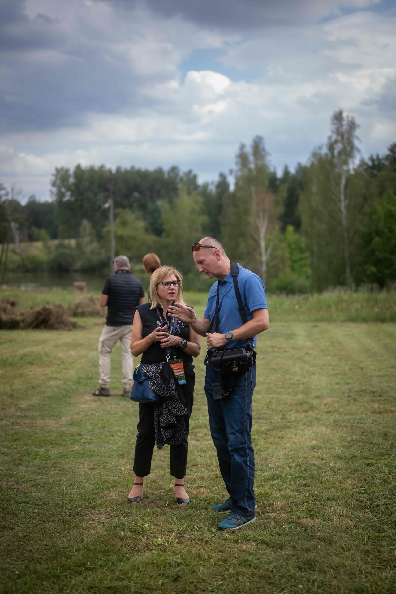 Two attendees talking on the demo field by the pond