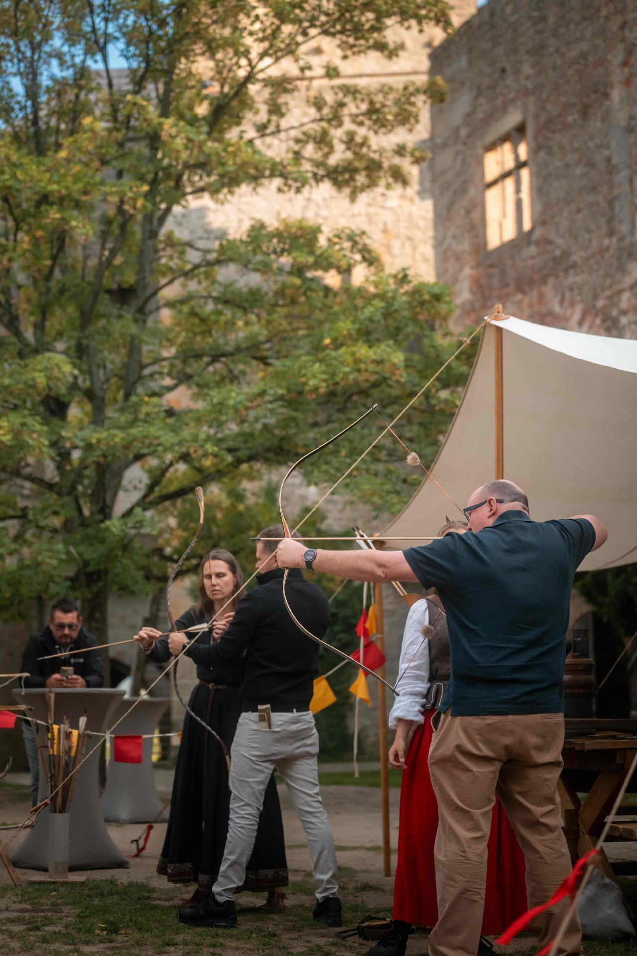 Attendee aiming a longbow next to the tent in the courtyard