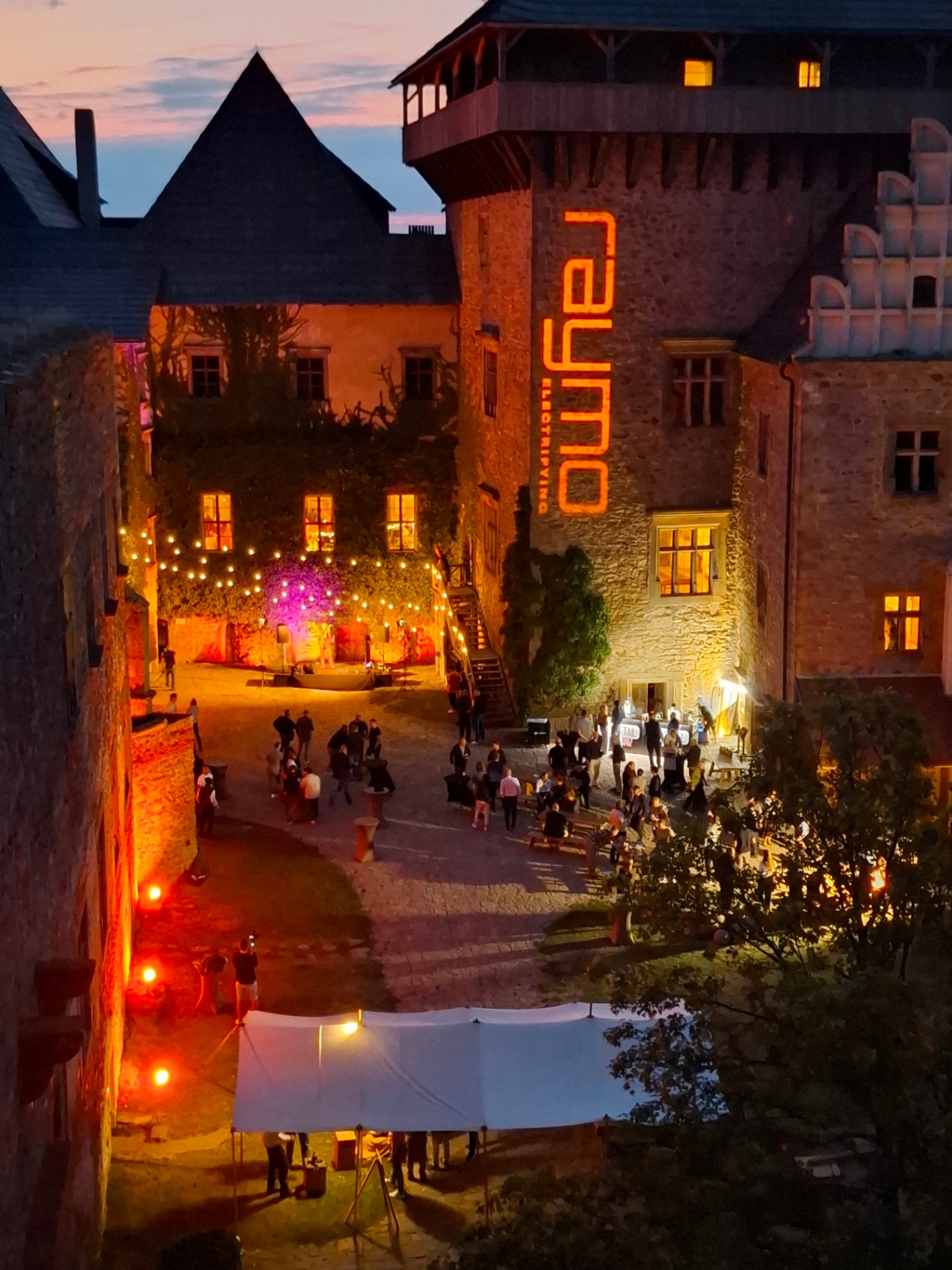 Castle Lipnice courtyard at dusk with the Raymo logo projected on the tower