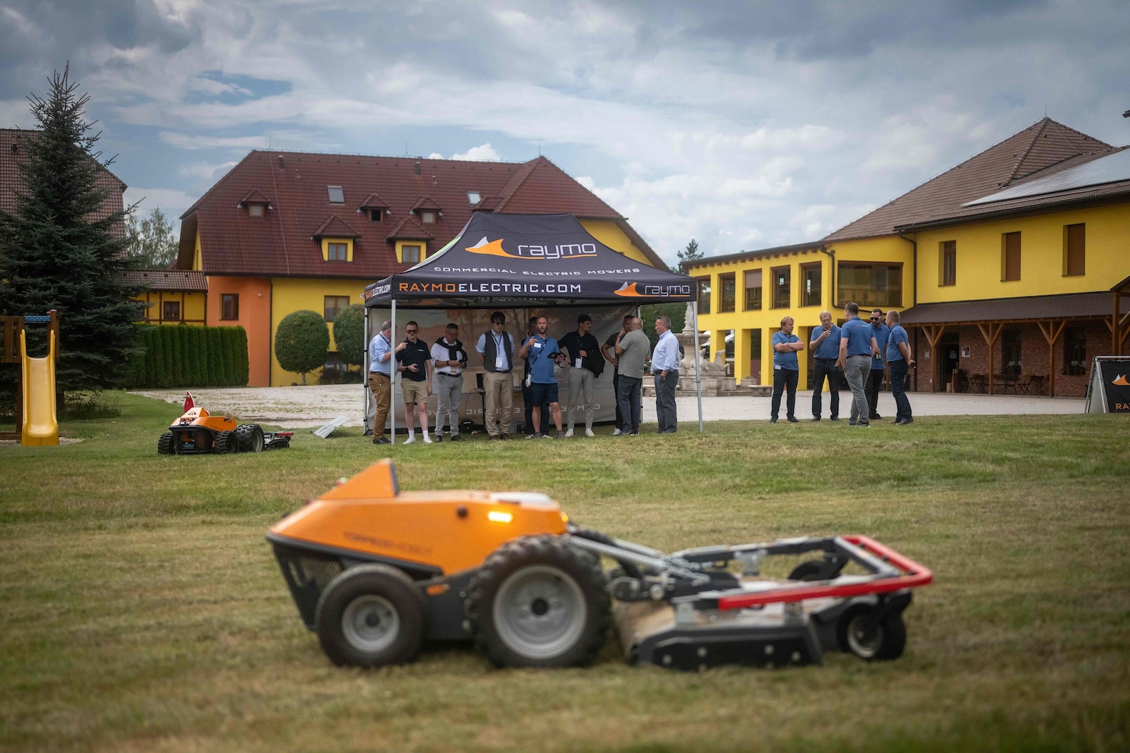 Attendees under the Raymo Electric tent watching machines work on the lawn