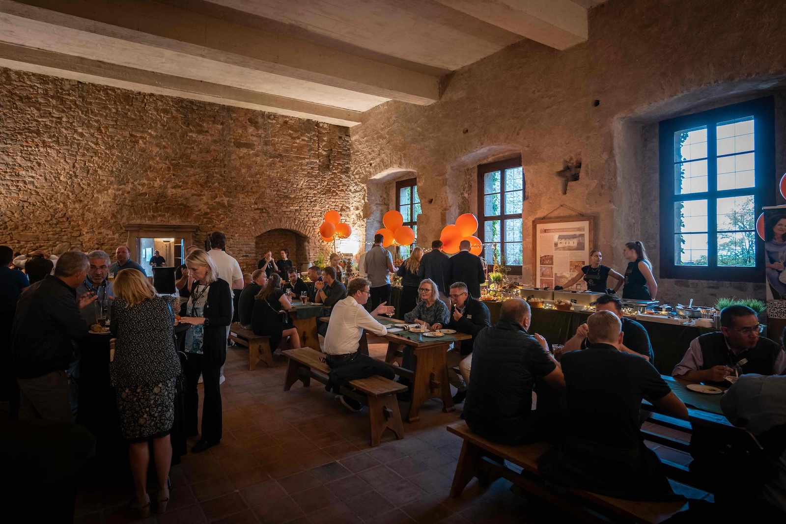 Full castle hall with guests eating at long wooden tables