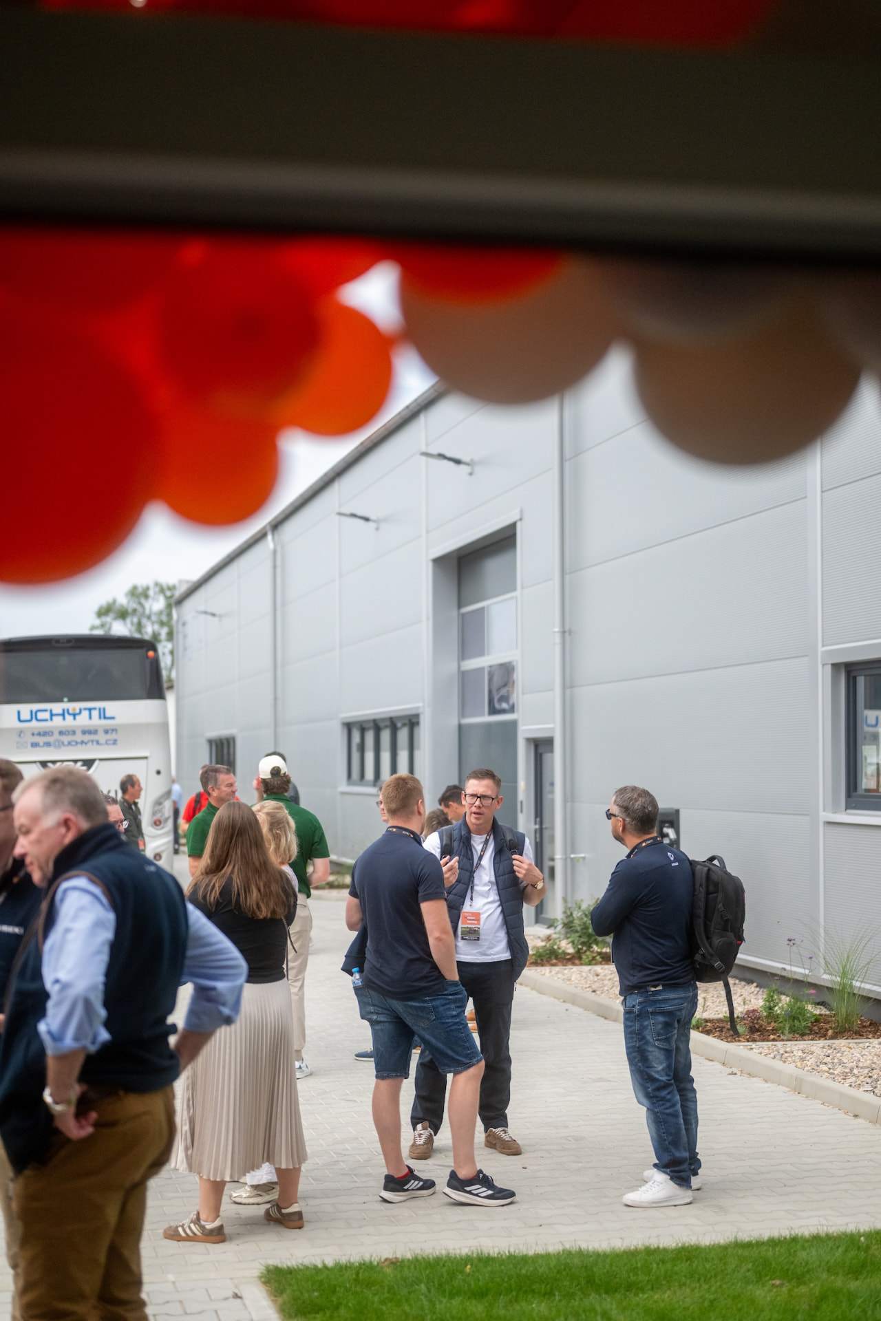 Guests talking outside the new hall seen through the orange balloon arch