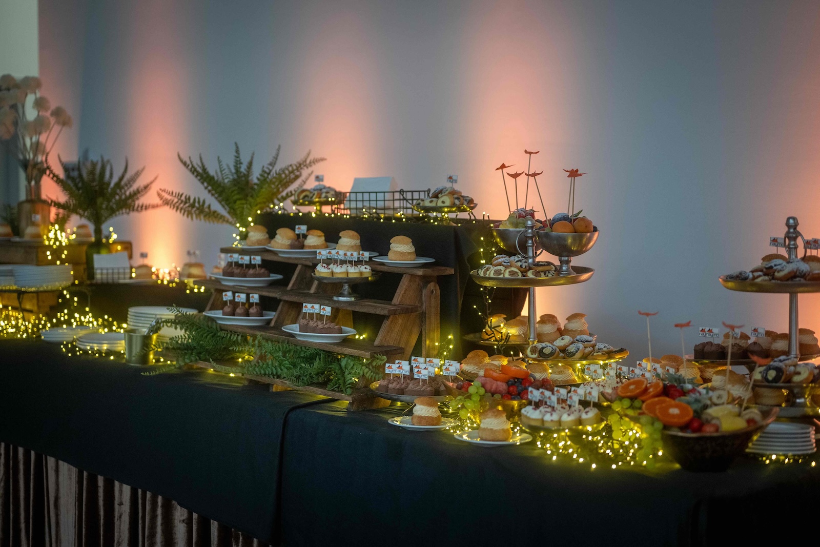 Dessert buffet with fairy lights, ferns and Raymo flagged pastries