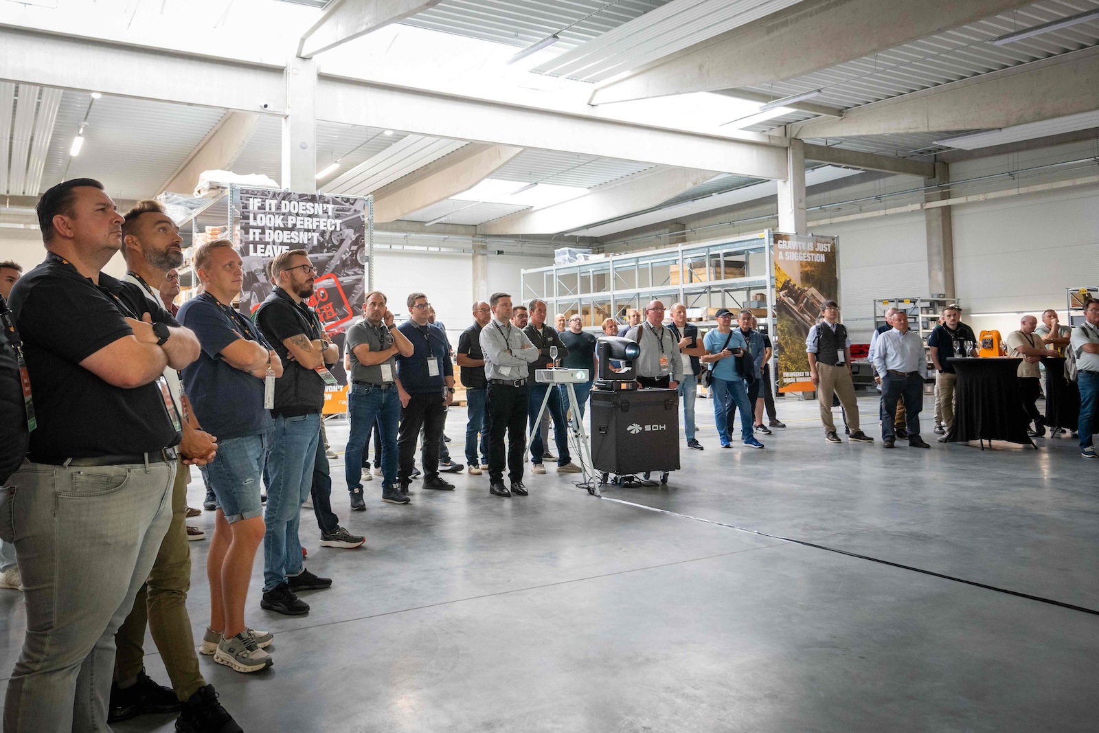 Wide view of the audience standing in the new warehouse hall during the opening presentation