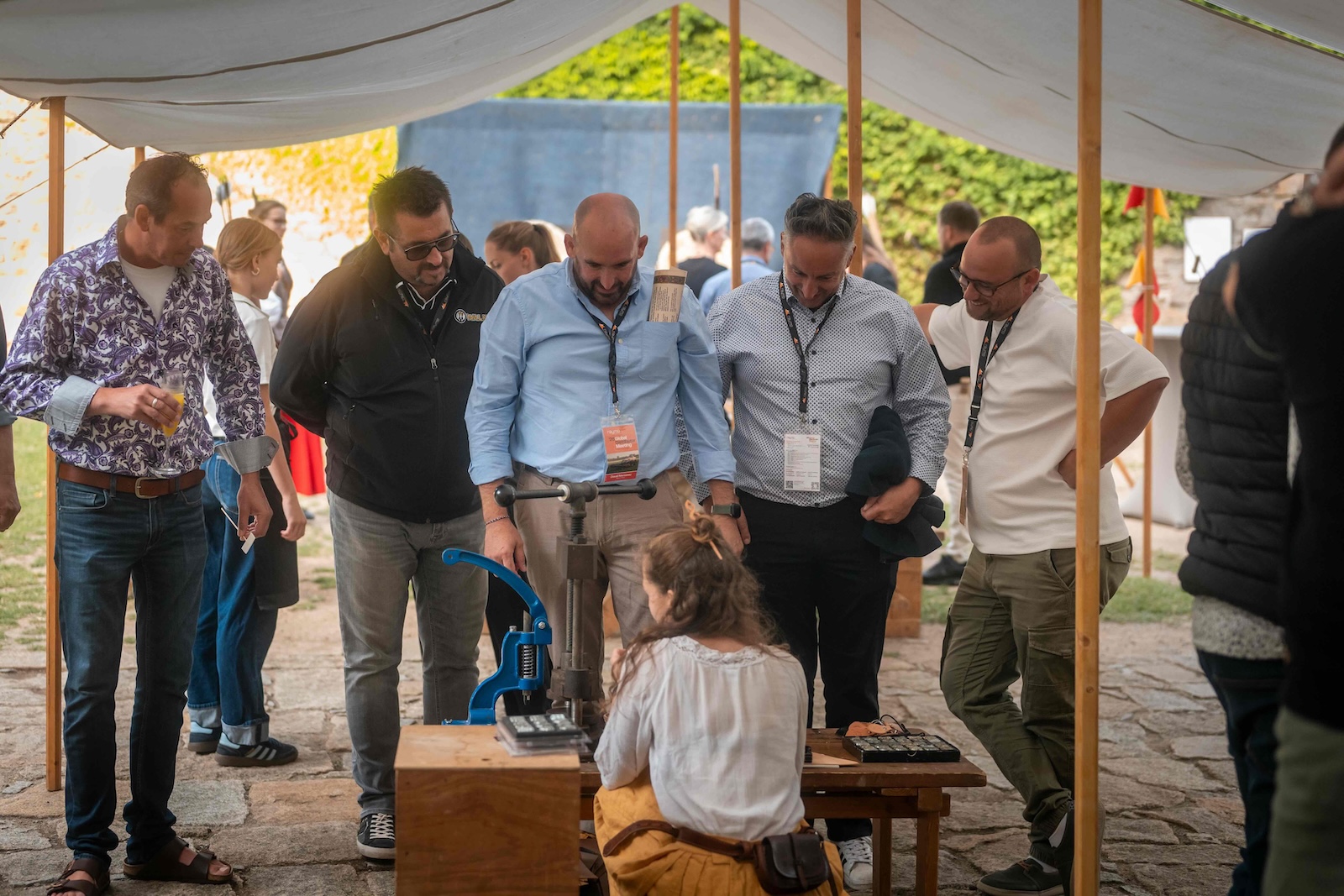 Group of guests watching the leather stamping workshop under the tent