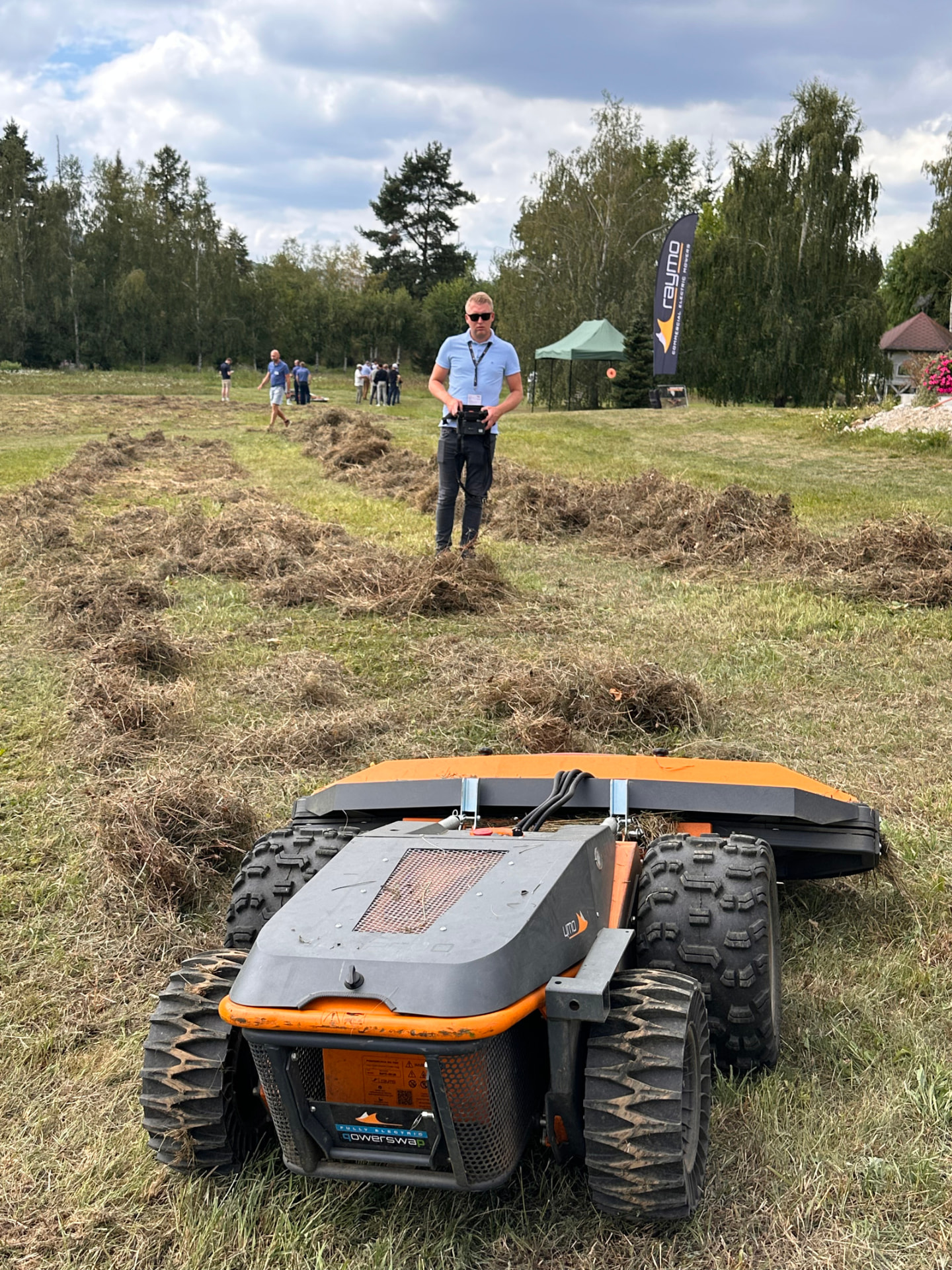 Operator remote-controlling a Raymo mower in the mown field