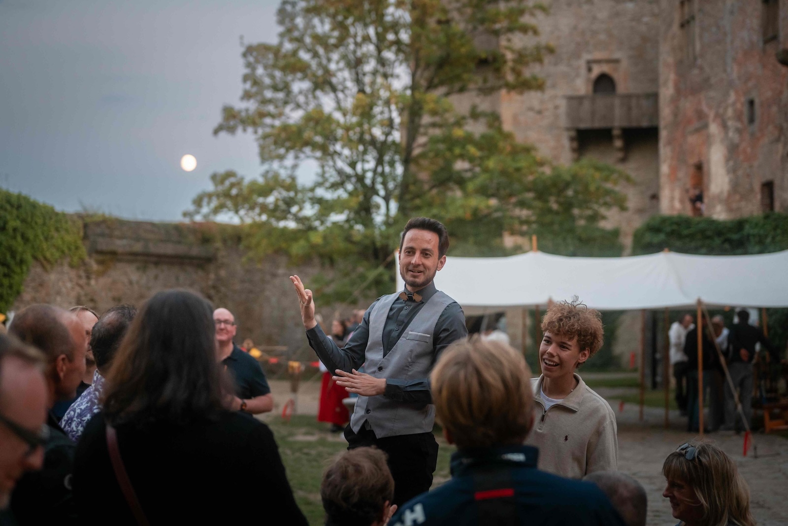 Host entertaining the audience with the full moon over the castle wall