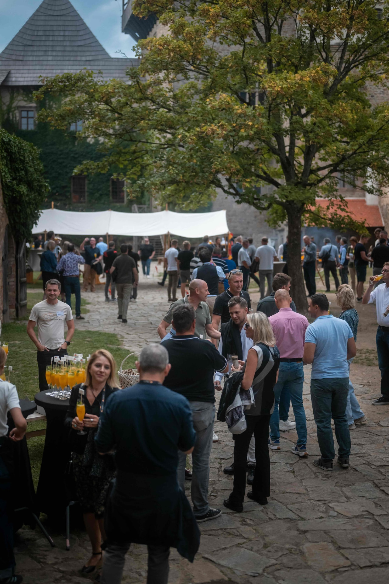Attendees mingling in the castle courtyard under the trees