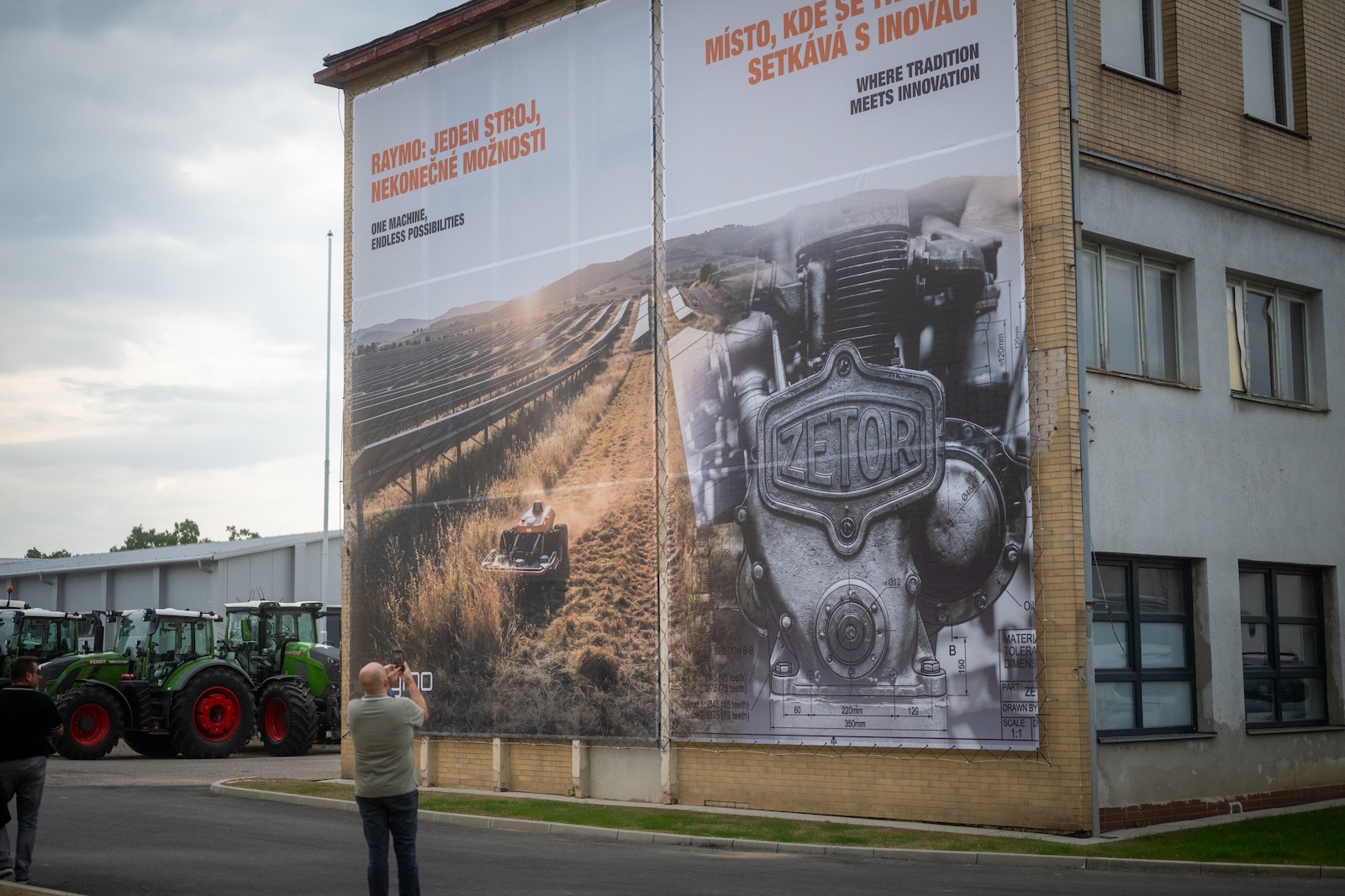 Guest photographing the large Raymo and Zetor banner on the building facade