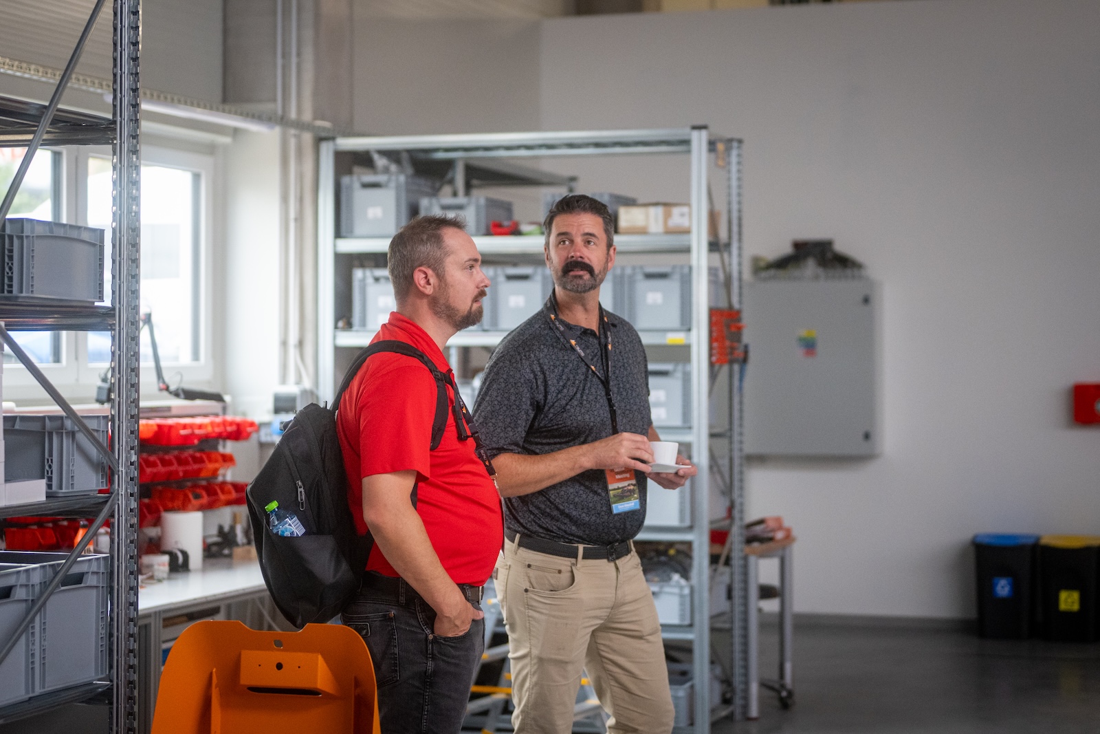 Two attendees with coffee in the assembly area