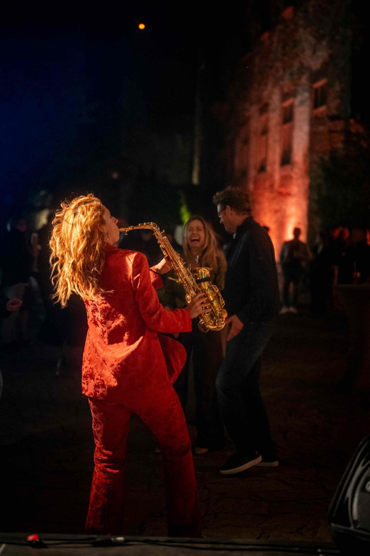 Saxophonist playing among dancing guests