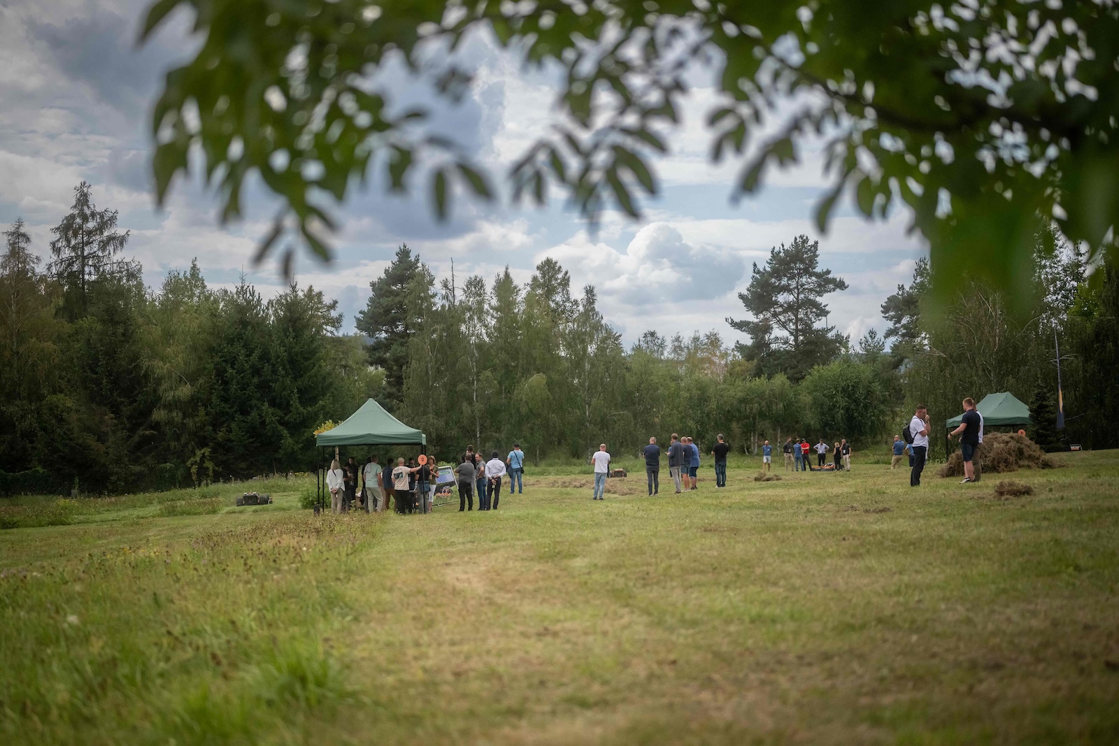 Wide view over the demo meadow with tents and groups of attendees