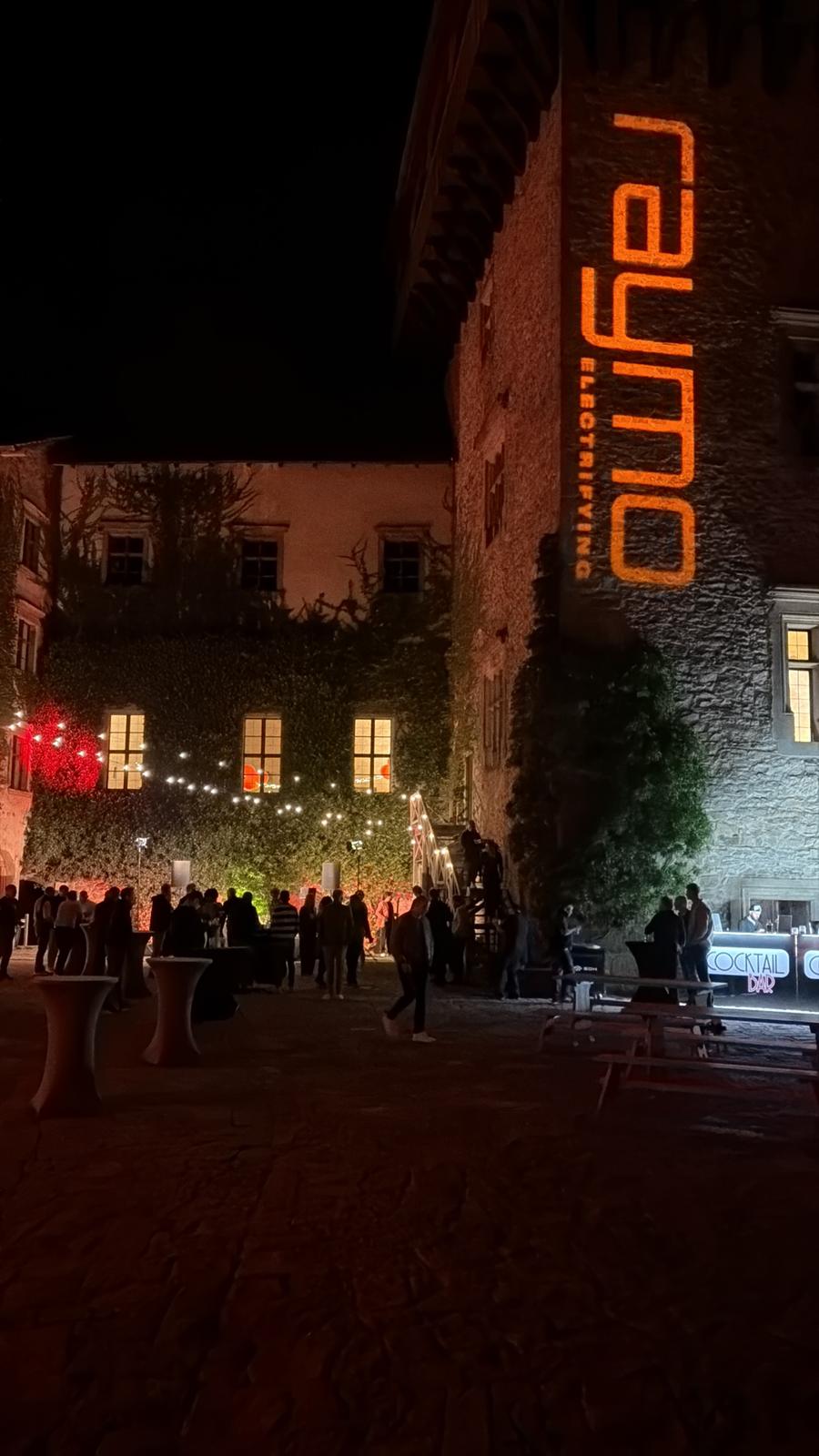 Cocktail bar and guests below the projected Raymo logo