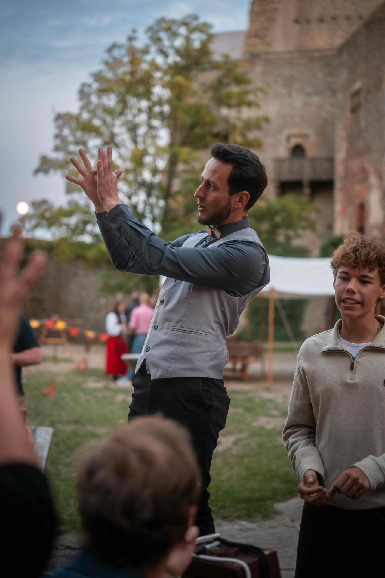Performer conducting the audience with raised hands at the castle
