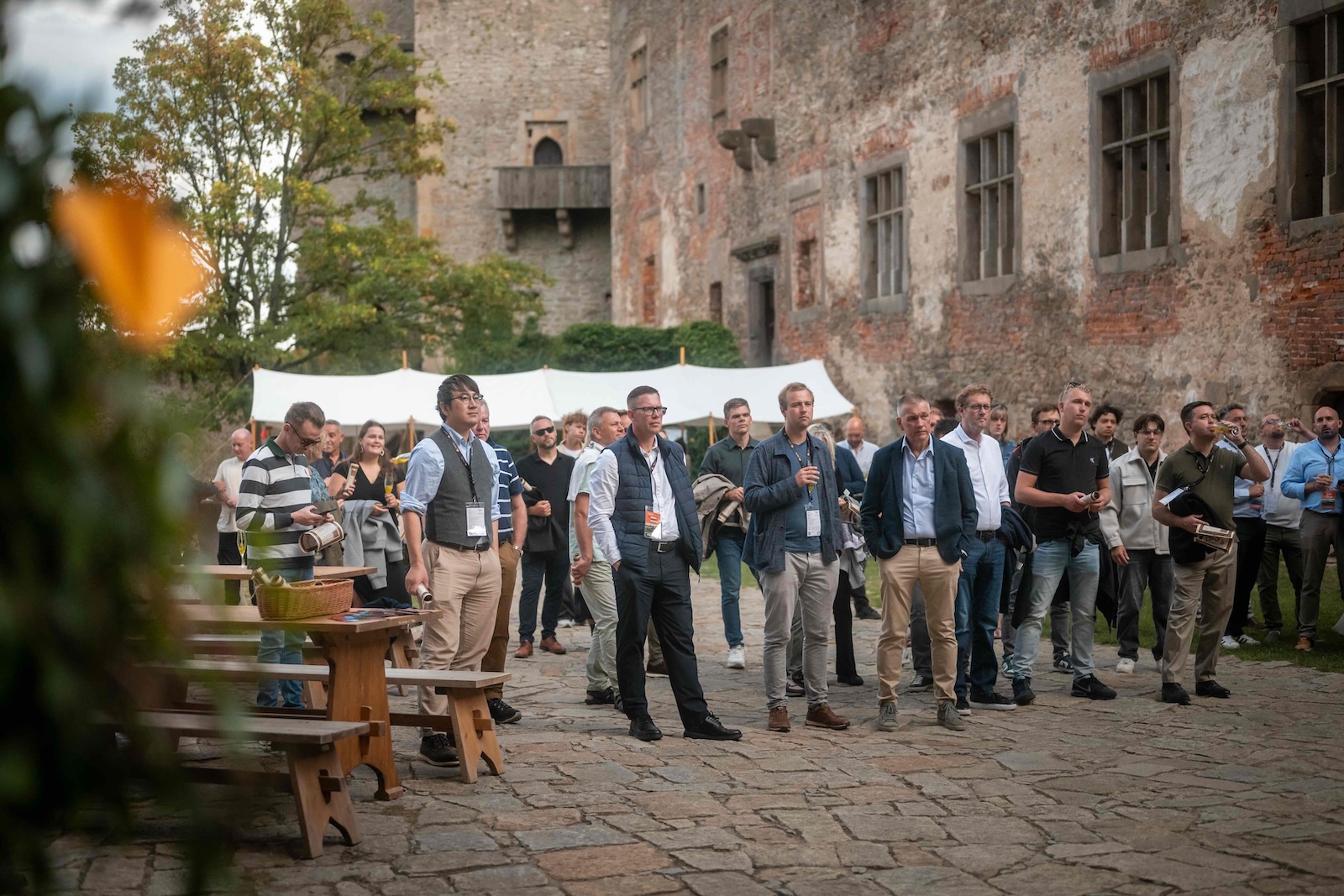 Attendees gathered by wooden benches in front of the castle walls