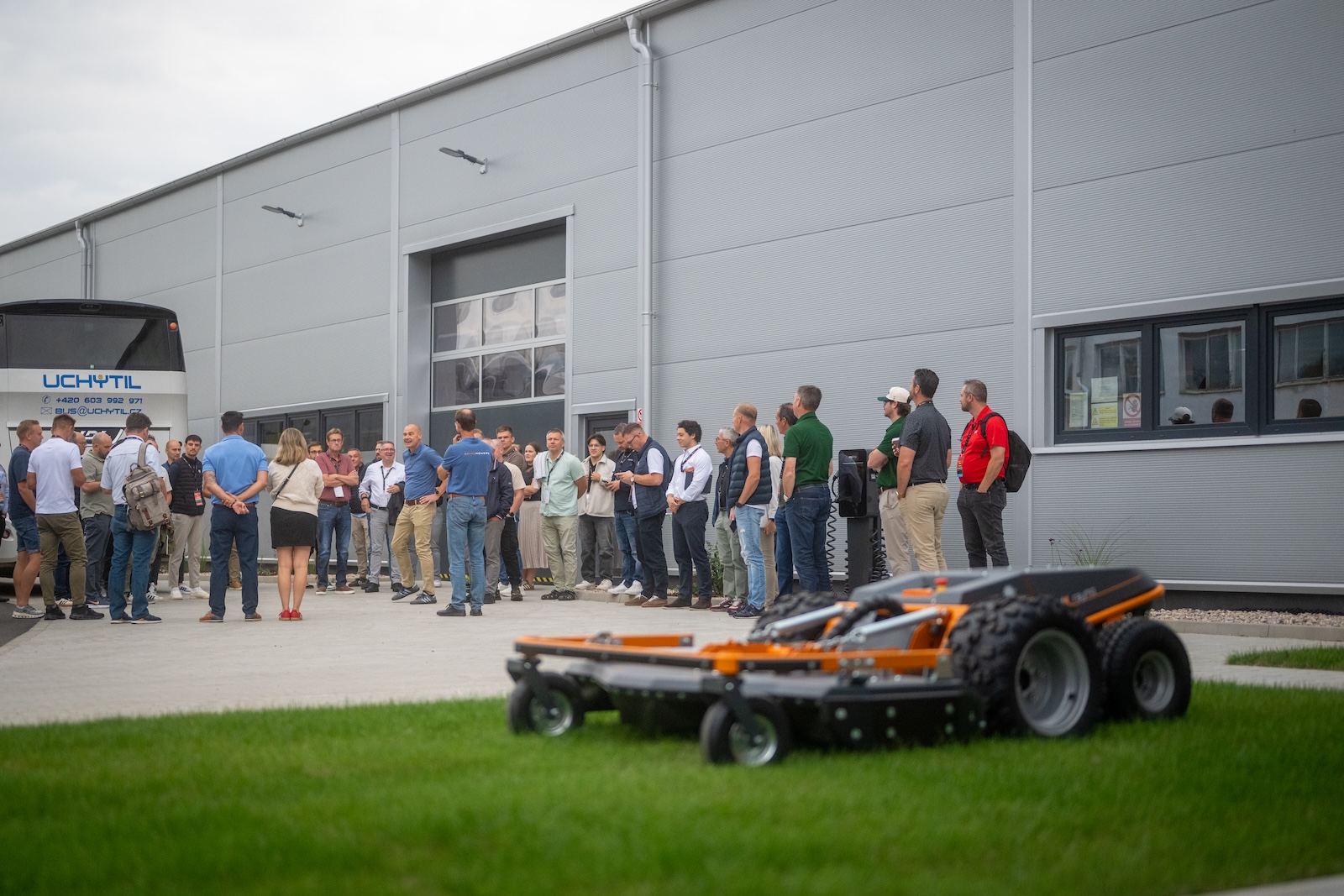 Guests in front of the new Raymo hall with a mower on the lawn
