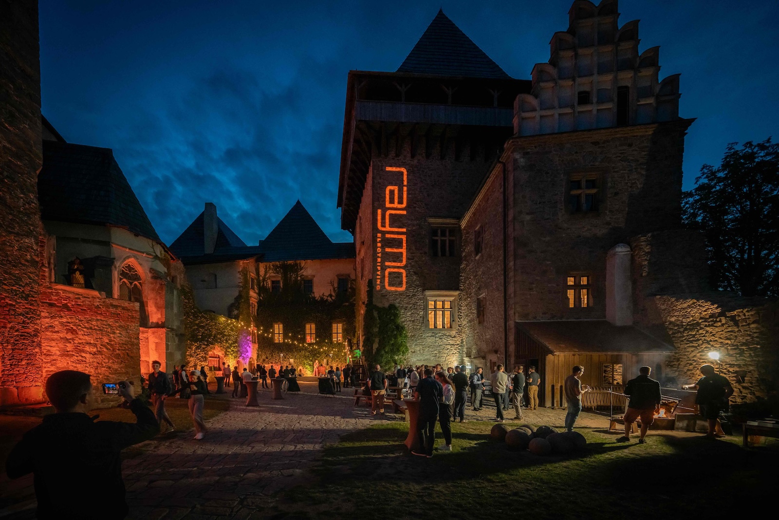 Castle Lipnice courtyard at blue hour with the Raymo logo lit on the tower