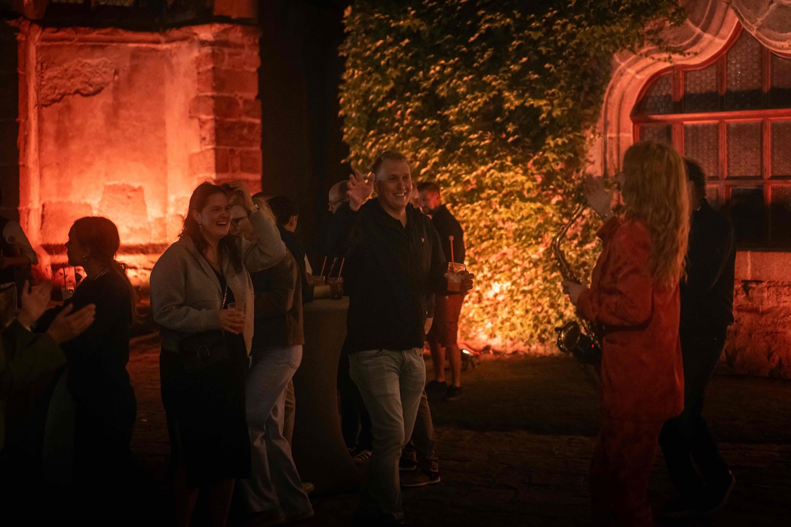 Guests applauding the saxophonist in the lit courtyard