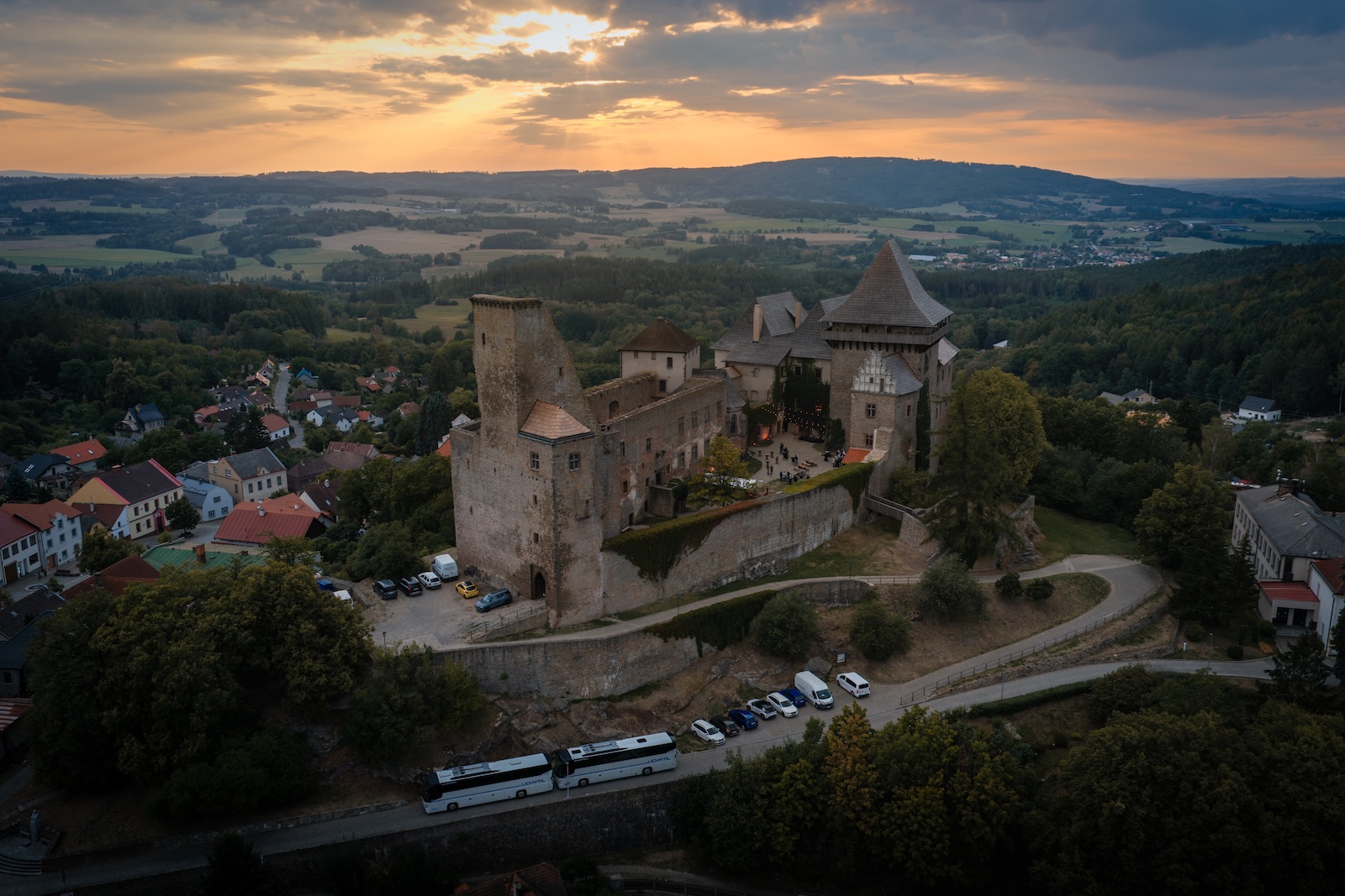 Aerial view of Lipnice Castle at sunset with coaches arriving