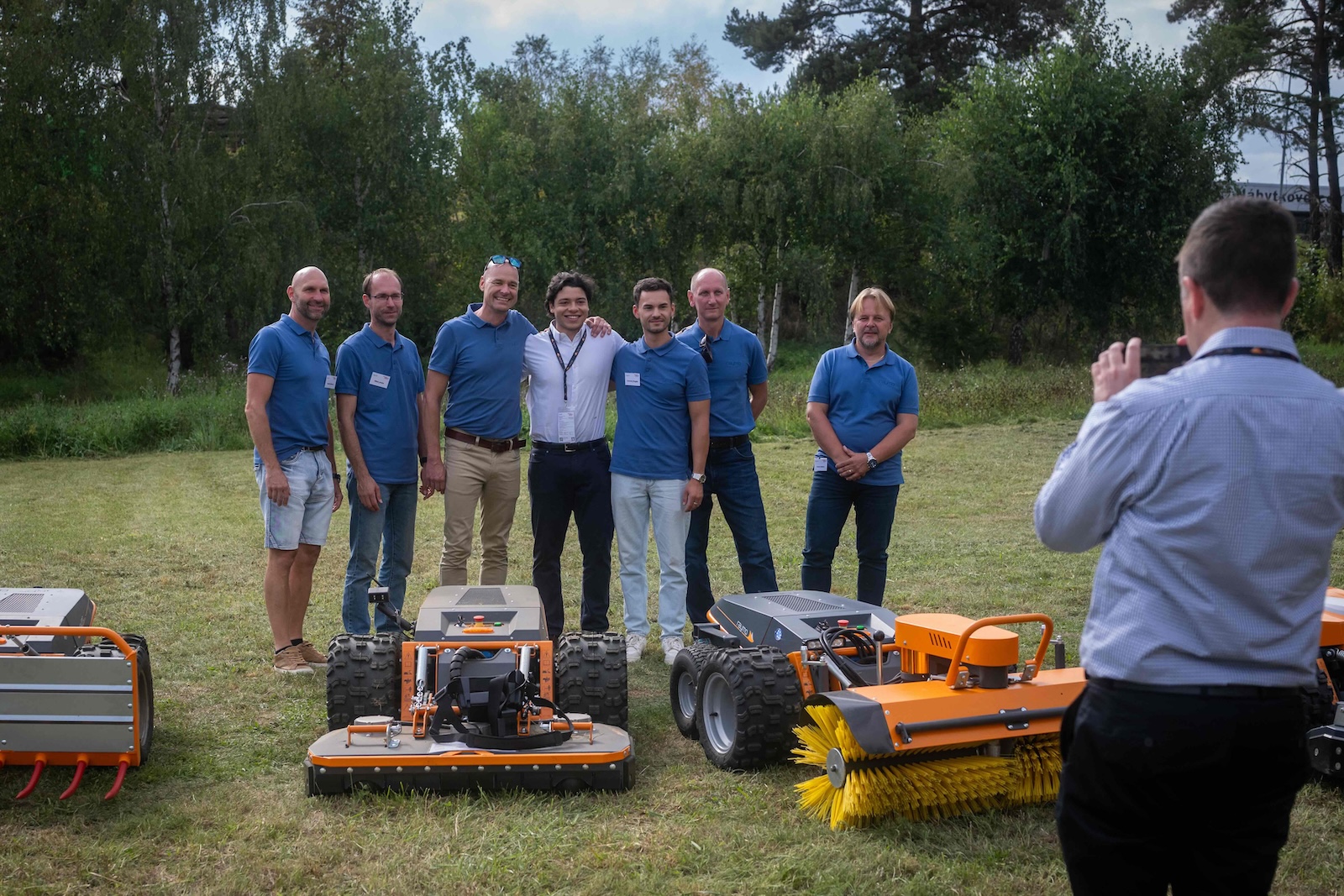 Raymo team photo with carriers, sweeper and mowing decks on the meadow